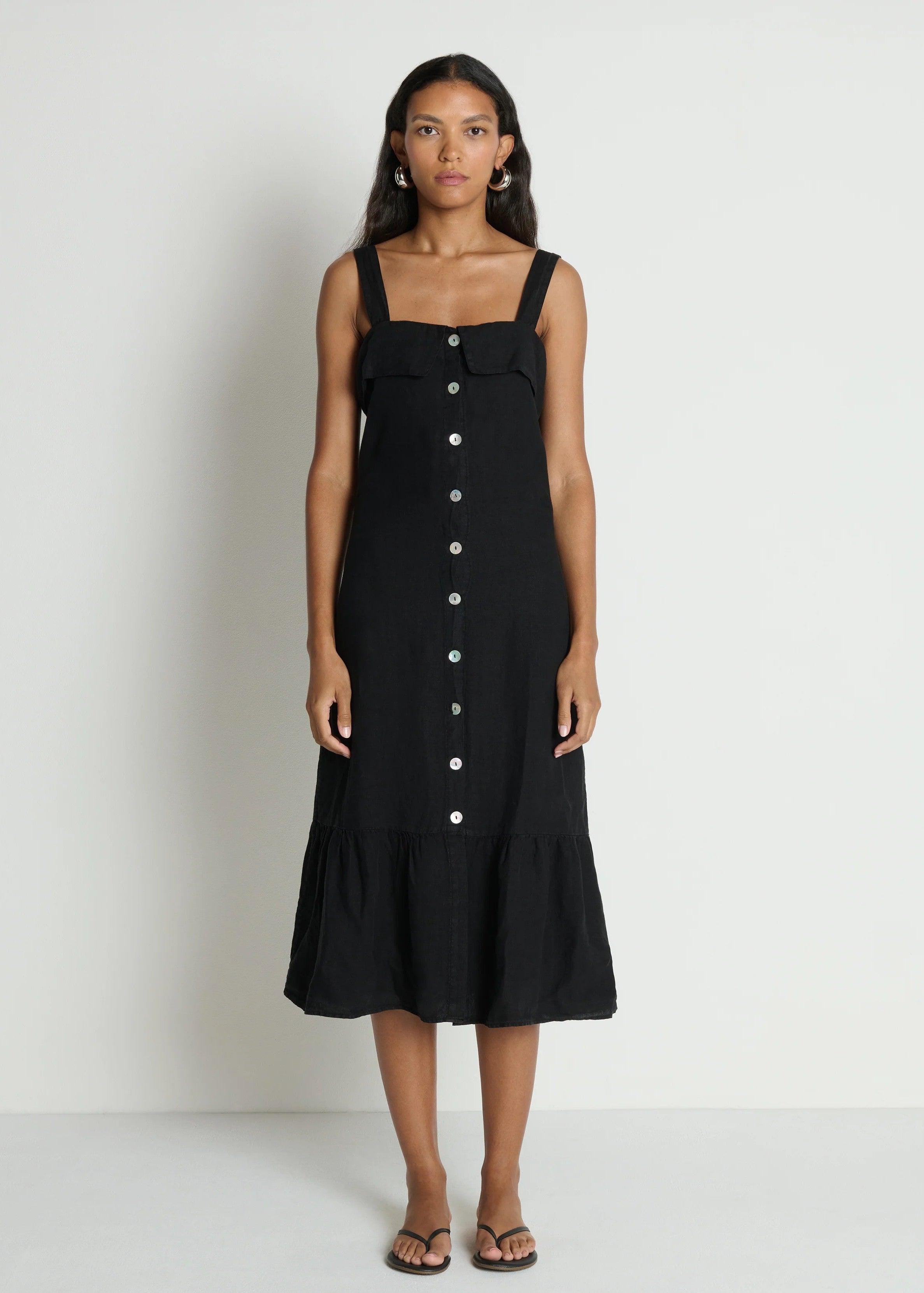Woman wearing a black dress with button details on a white background