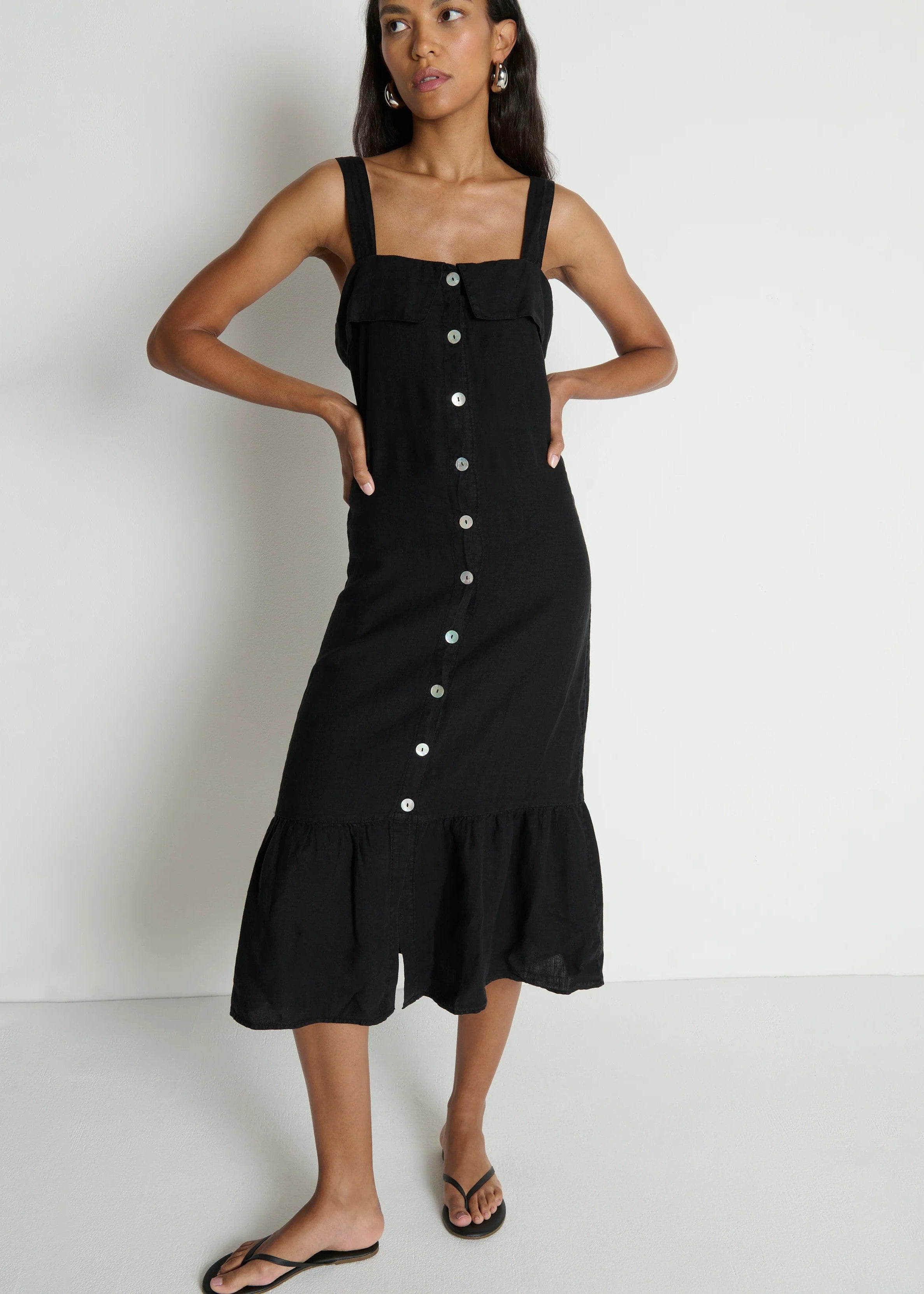 Woman wearing a black dress with buttons on a white background