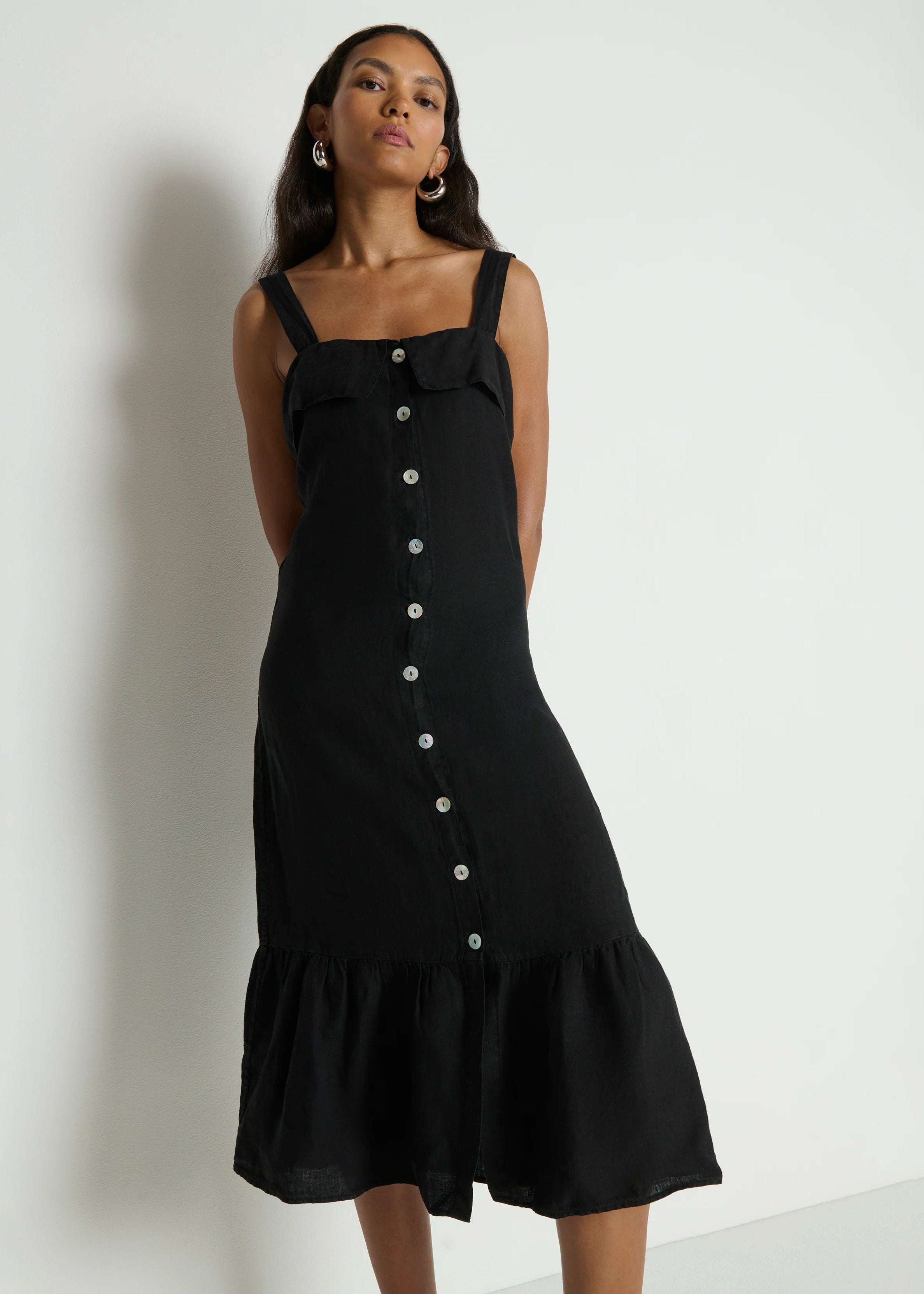 Woman wearing a black dress with buttons on a white background