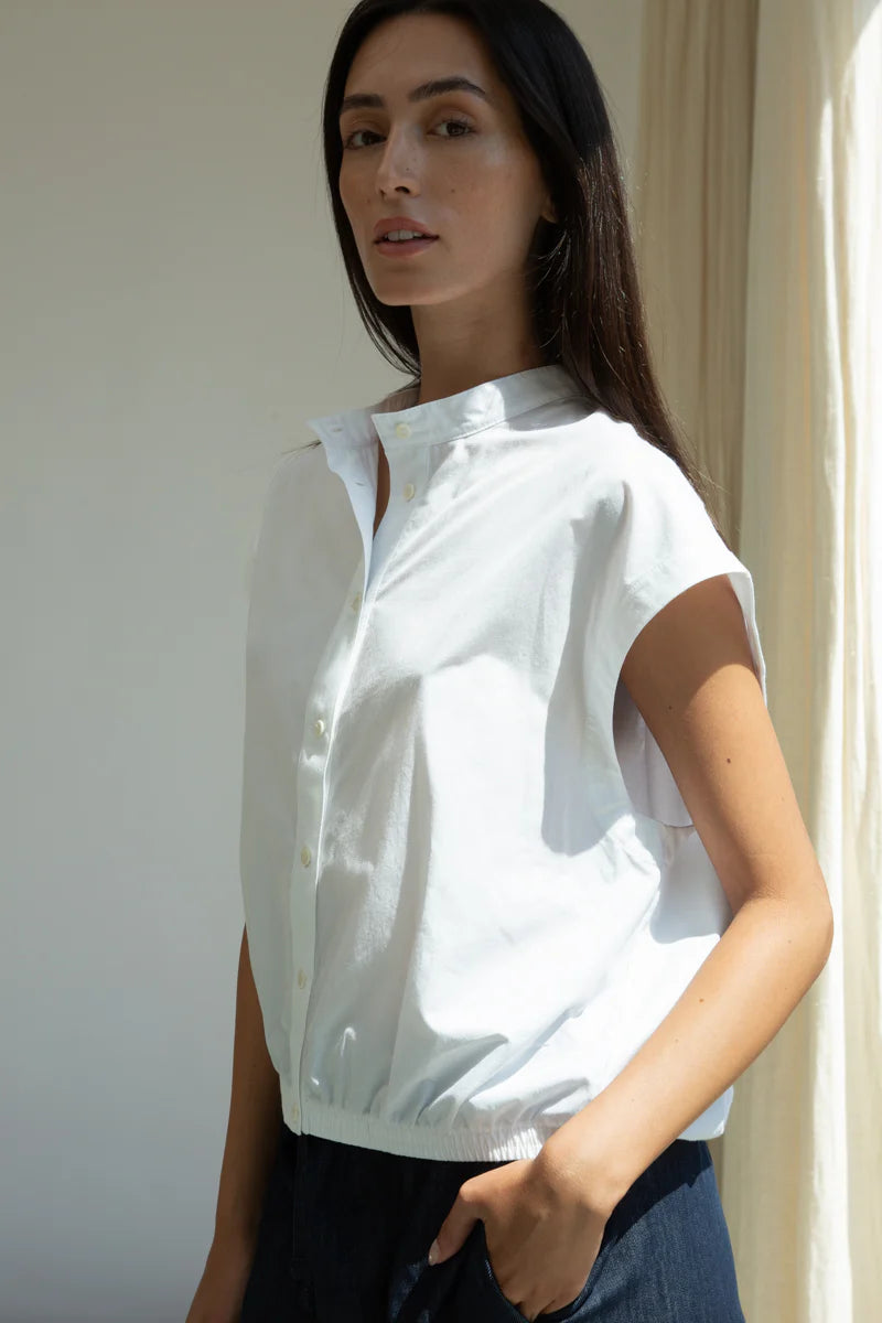 Woman wearing a white short-sleeve blouse against a neutral background
