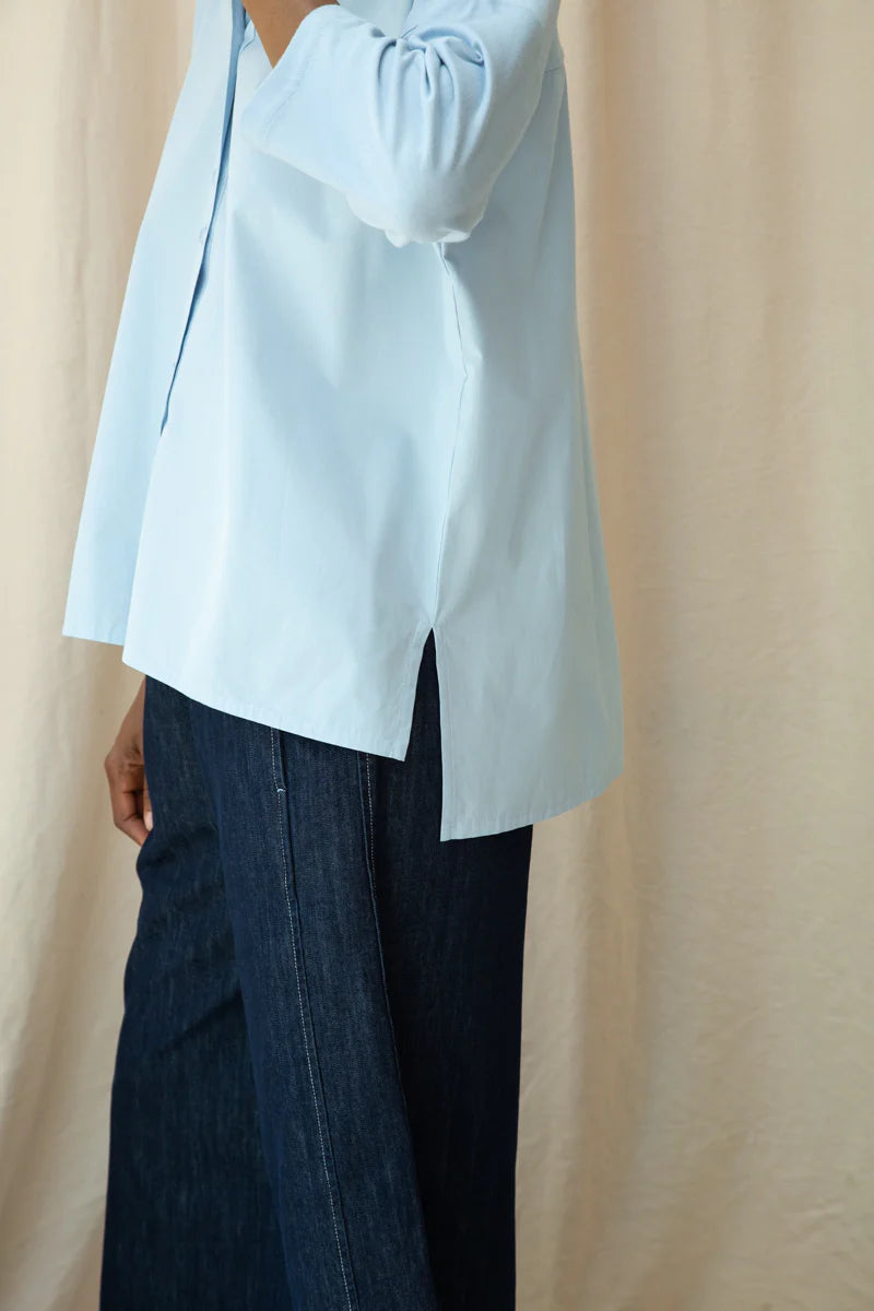 Light blue blouse and dark jeans against a beige background