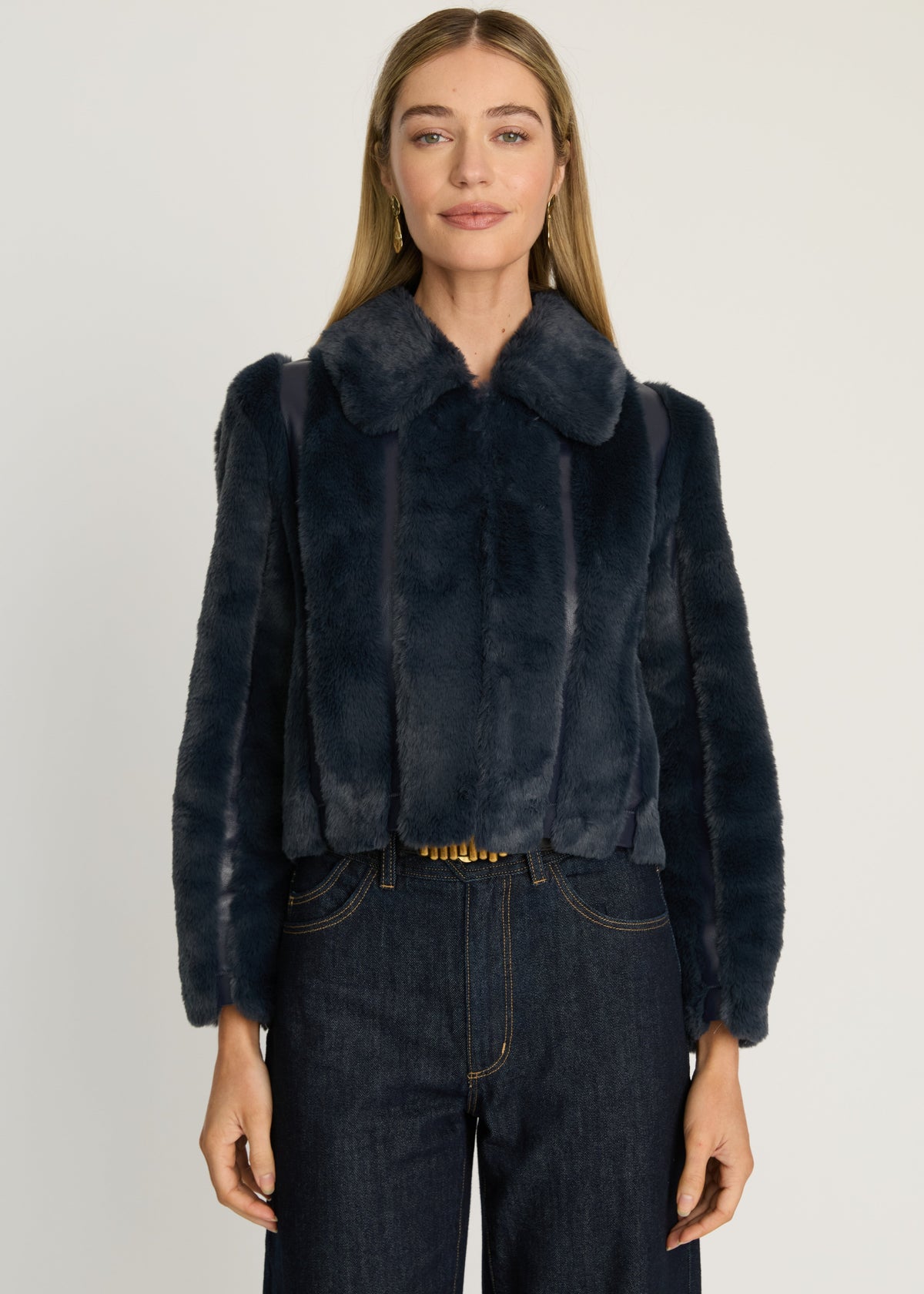 Woman wearing a dark blue fur coat against a plain background