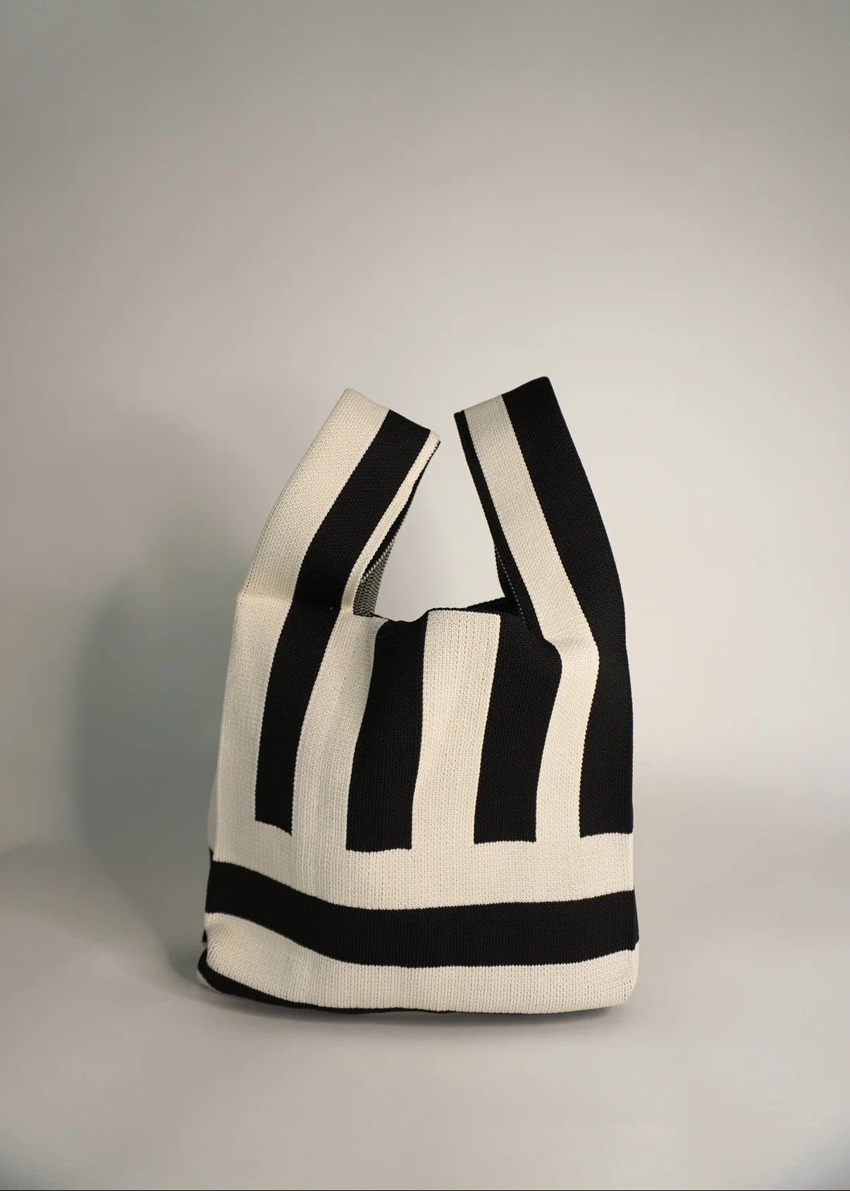 Black and white striped tote bag on a gray background