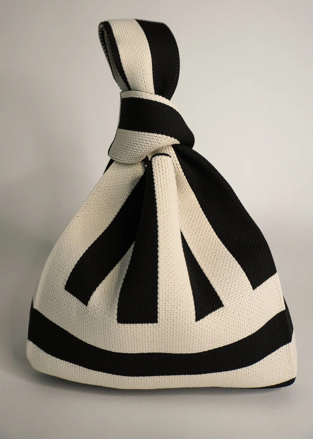 Black and white striped knitted bag on a gray background