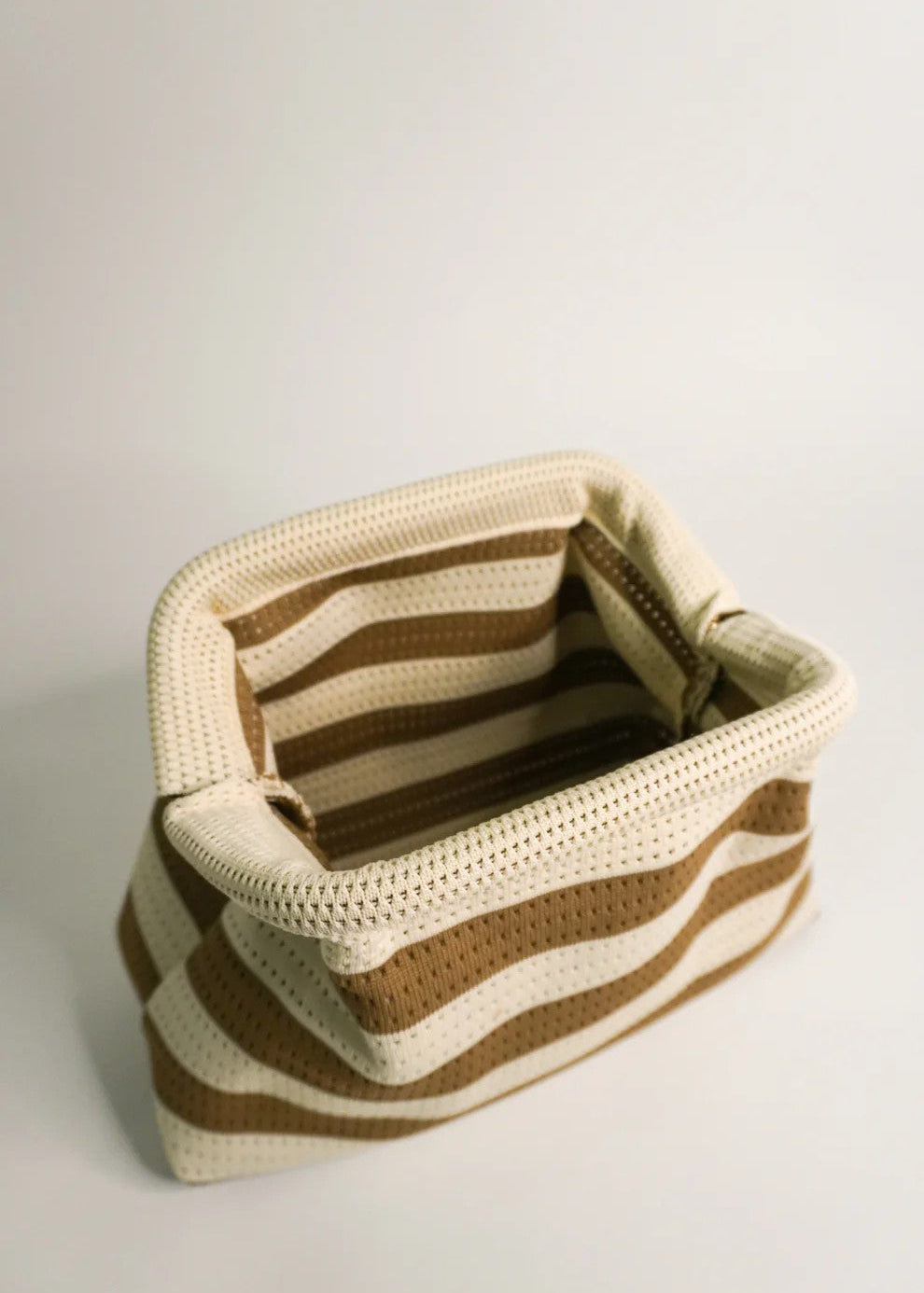 Crocheted basket with brown and beige stripes on a light gray background