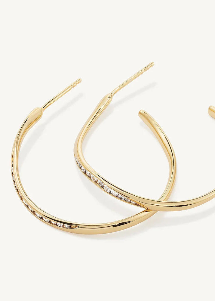 A pair of gold hoop earrings with a row of small clear stones along the front, displayed on a clean off-white background.
