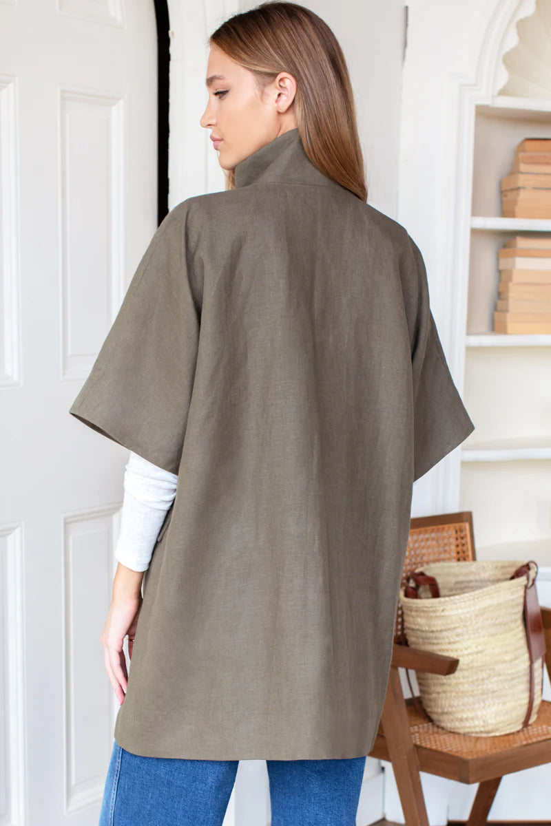 Woman wearing a brown poncho in a room with a chair and basket.