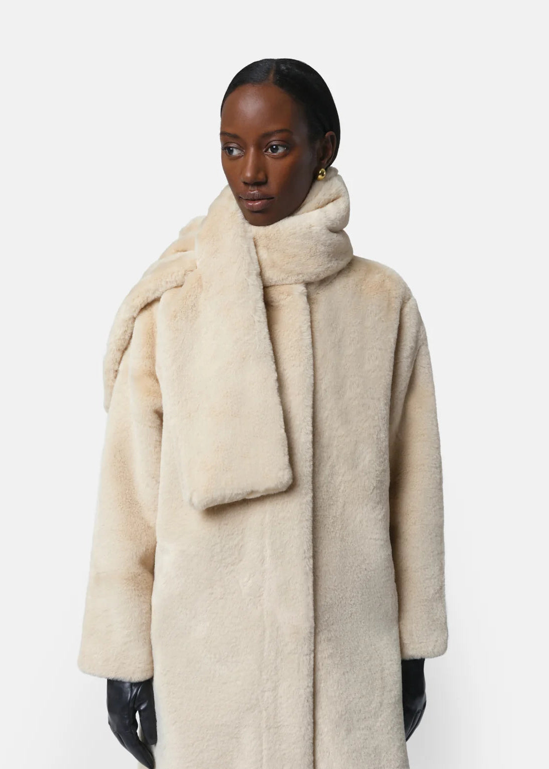 Person wearing a beige coat with a matching scarf on a white background
