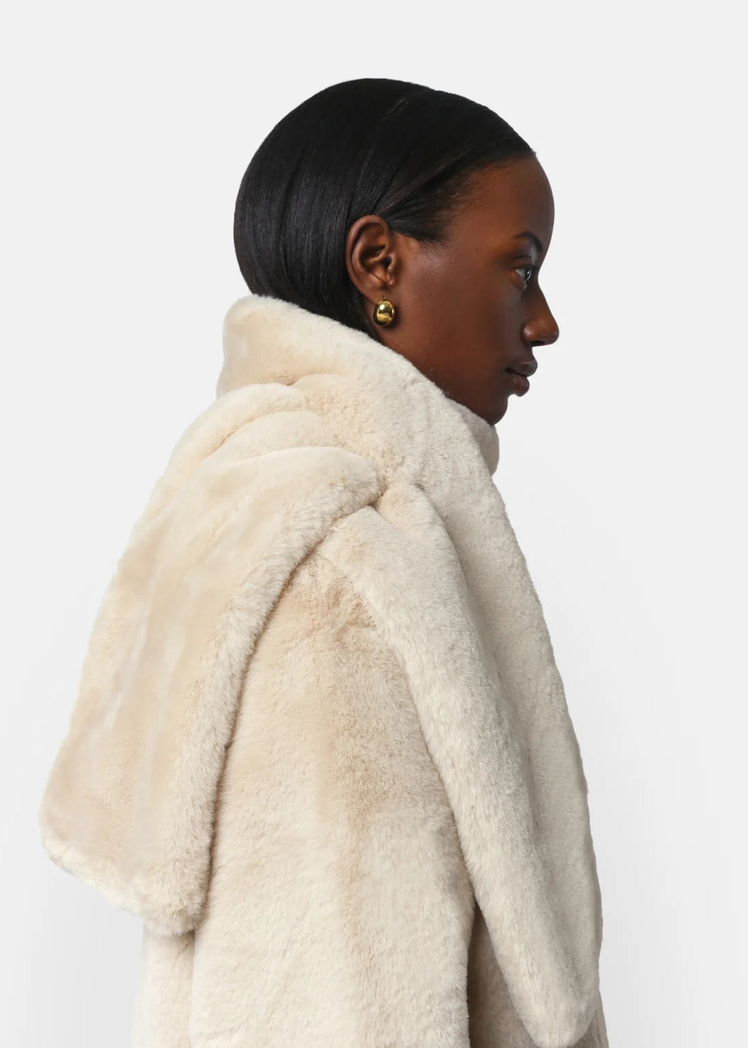 Woman wearing a cream fur coat on a white background