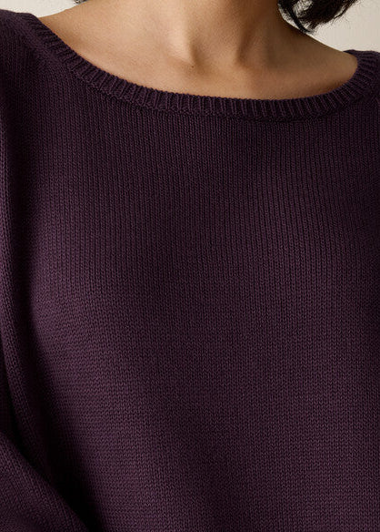 Close-up of a person wearing a dark plum purple ribbed knit sweater, showing the crew neck and textured fabric.