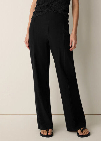 Person wearing black wide-leg pants on a neutral background
