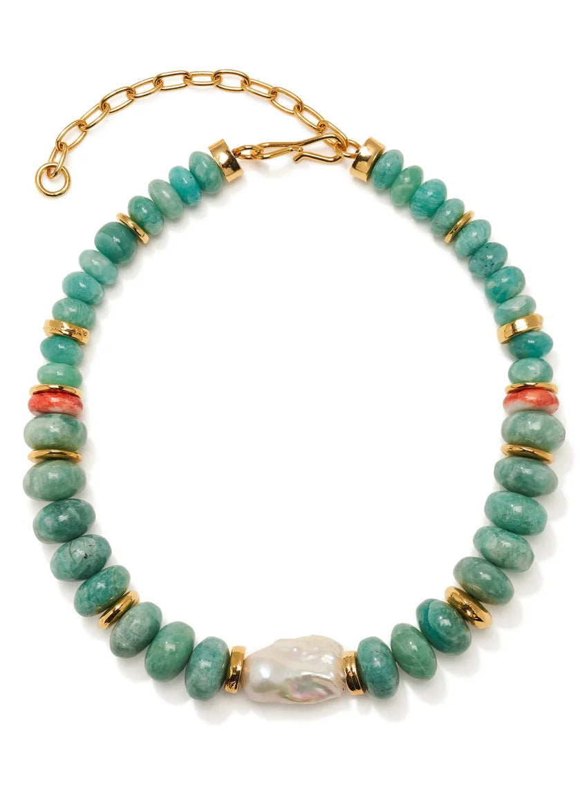 A beaded necklace featuring round turquoise-green beads, gold spacer discs, two small coral-red beads, and a central irregular white pearl-like bead, displayed on a clean white background.