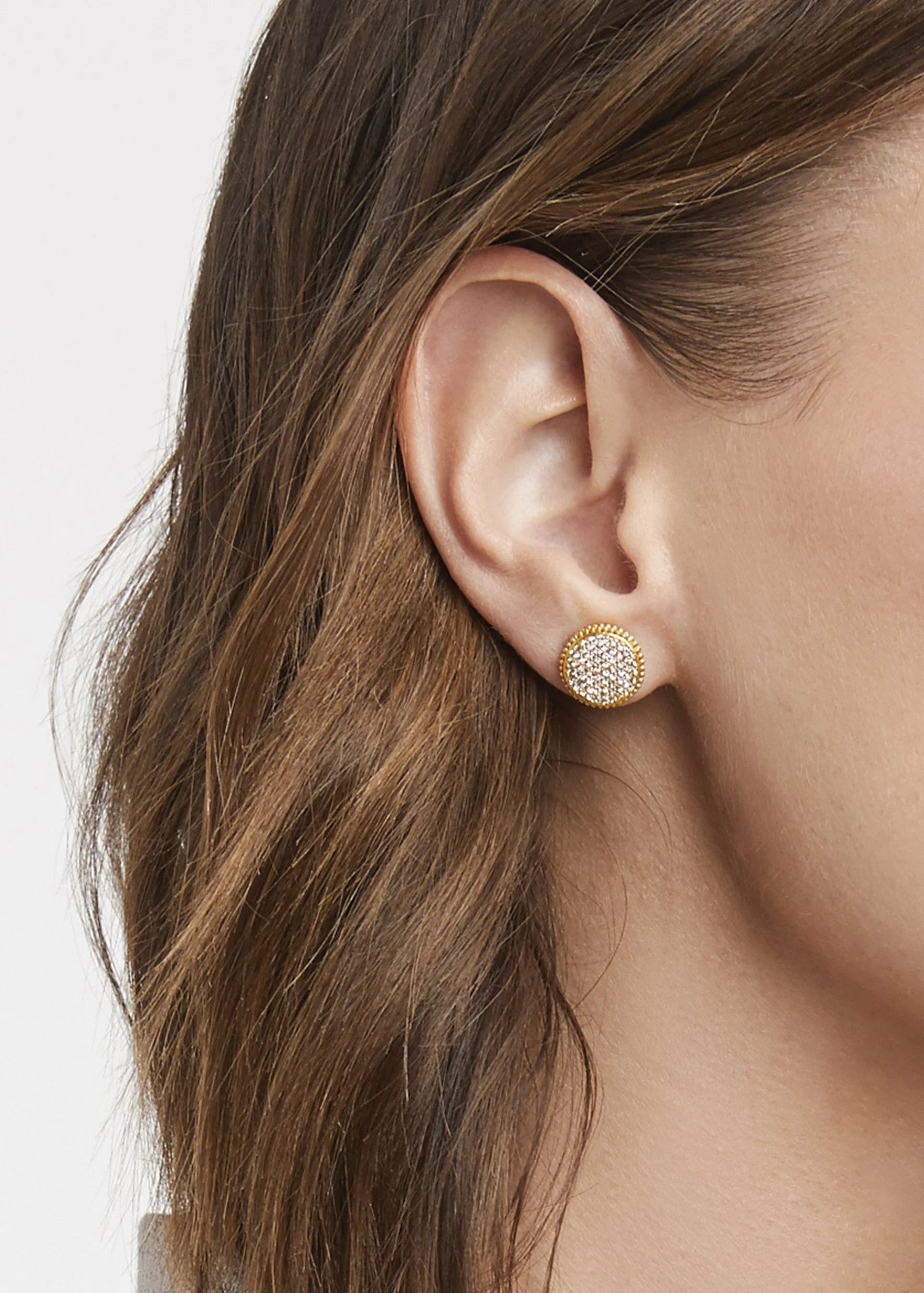 Close-up of a woman wearing gold earrings with a white background