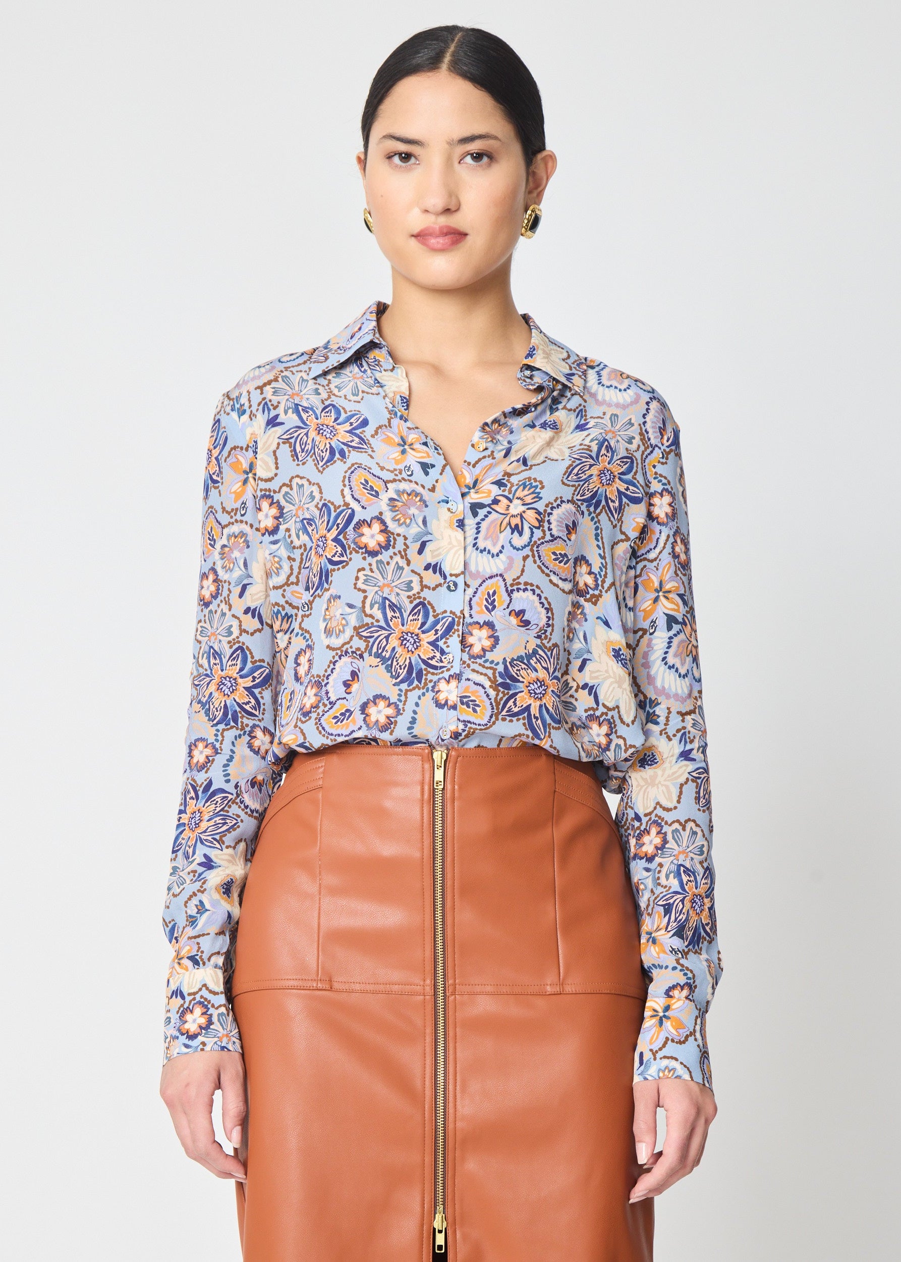 Woman wearing a floral blouse and brown leather skirt on a white background