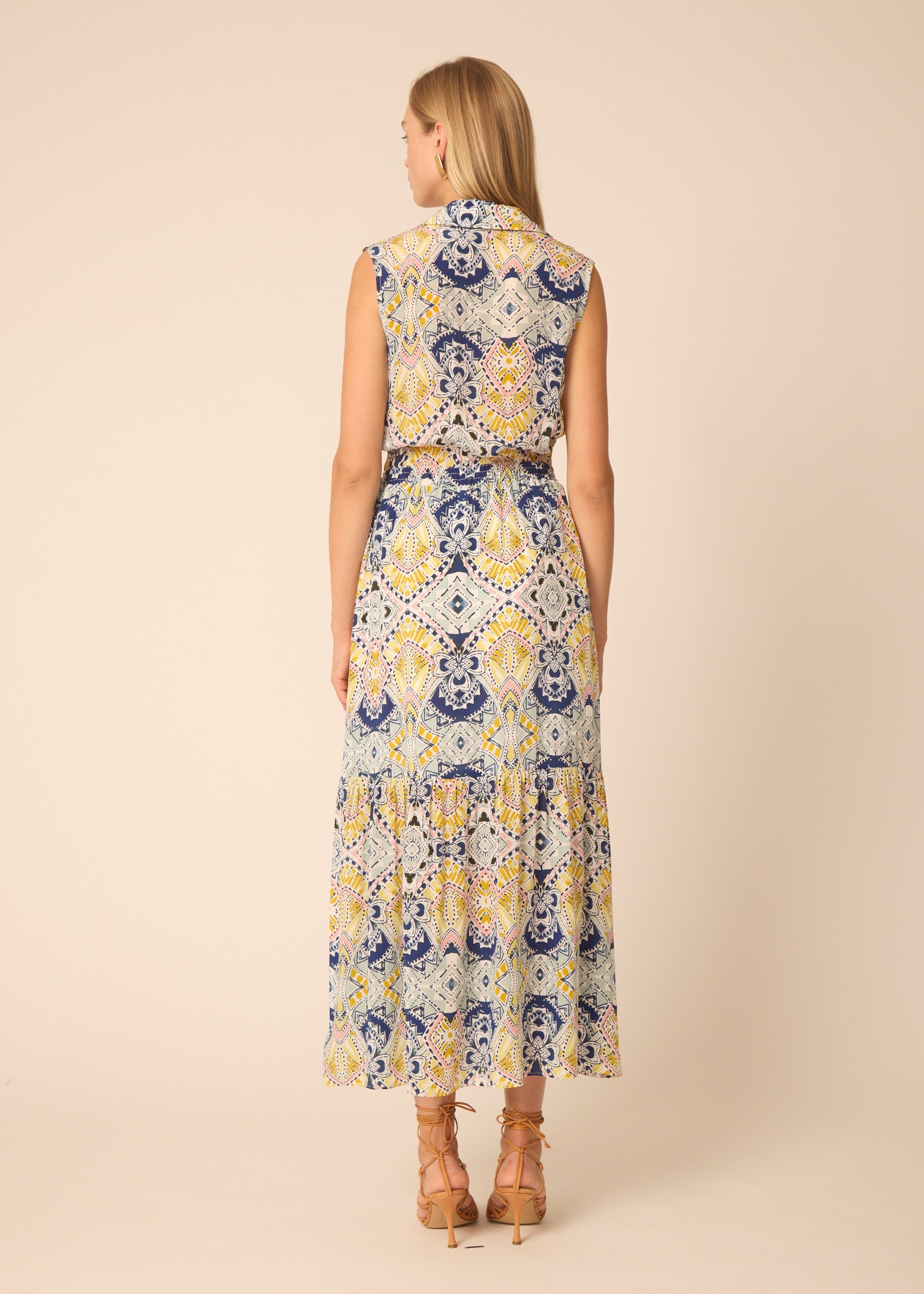 Woman wearing a sleeveless dress with a floral pattern on a beige background