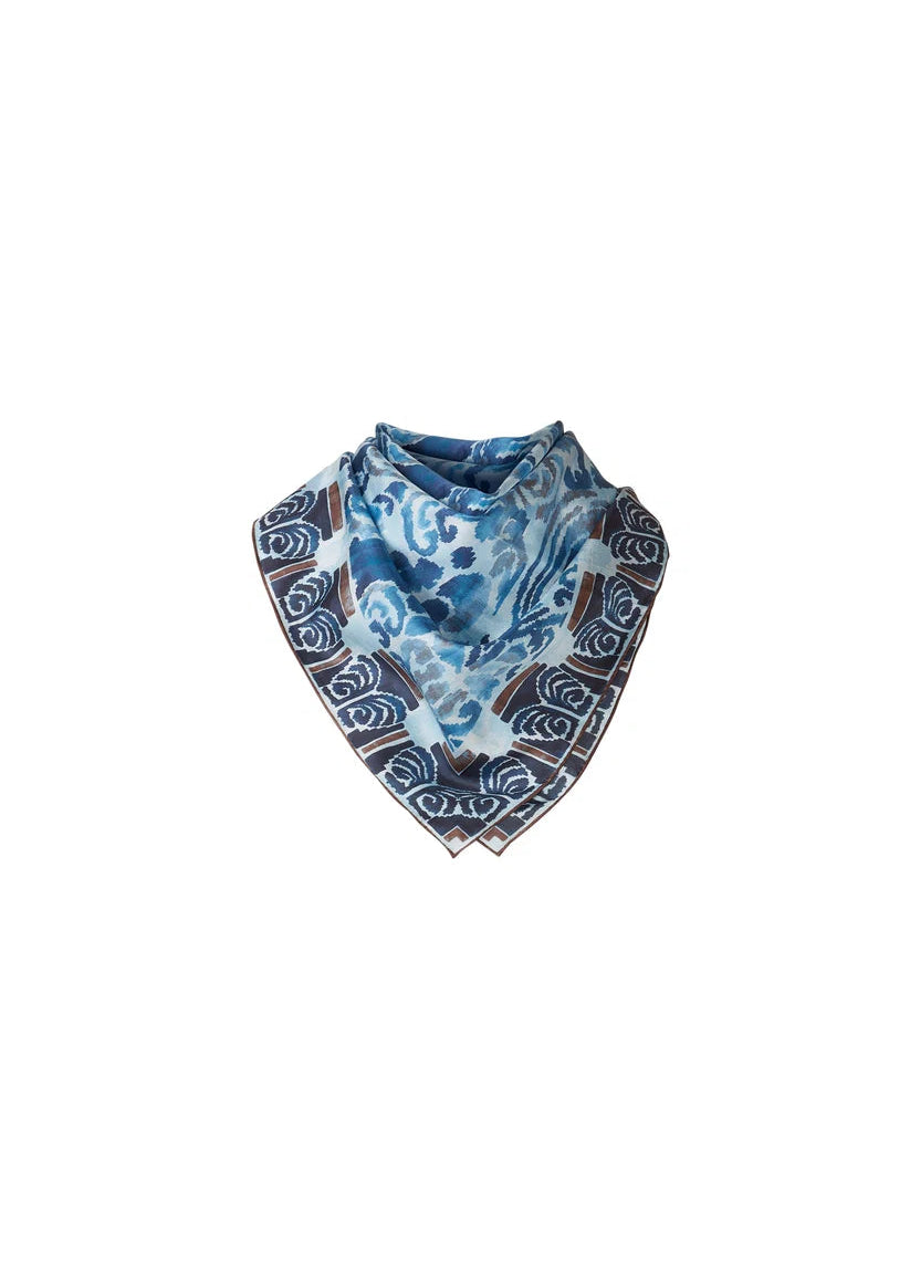 A square scarf with a blue and white abstract watercolor pattern and a dark brown border featuring white wave-like scroll designs, displayed on a solid white background.
