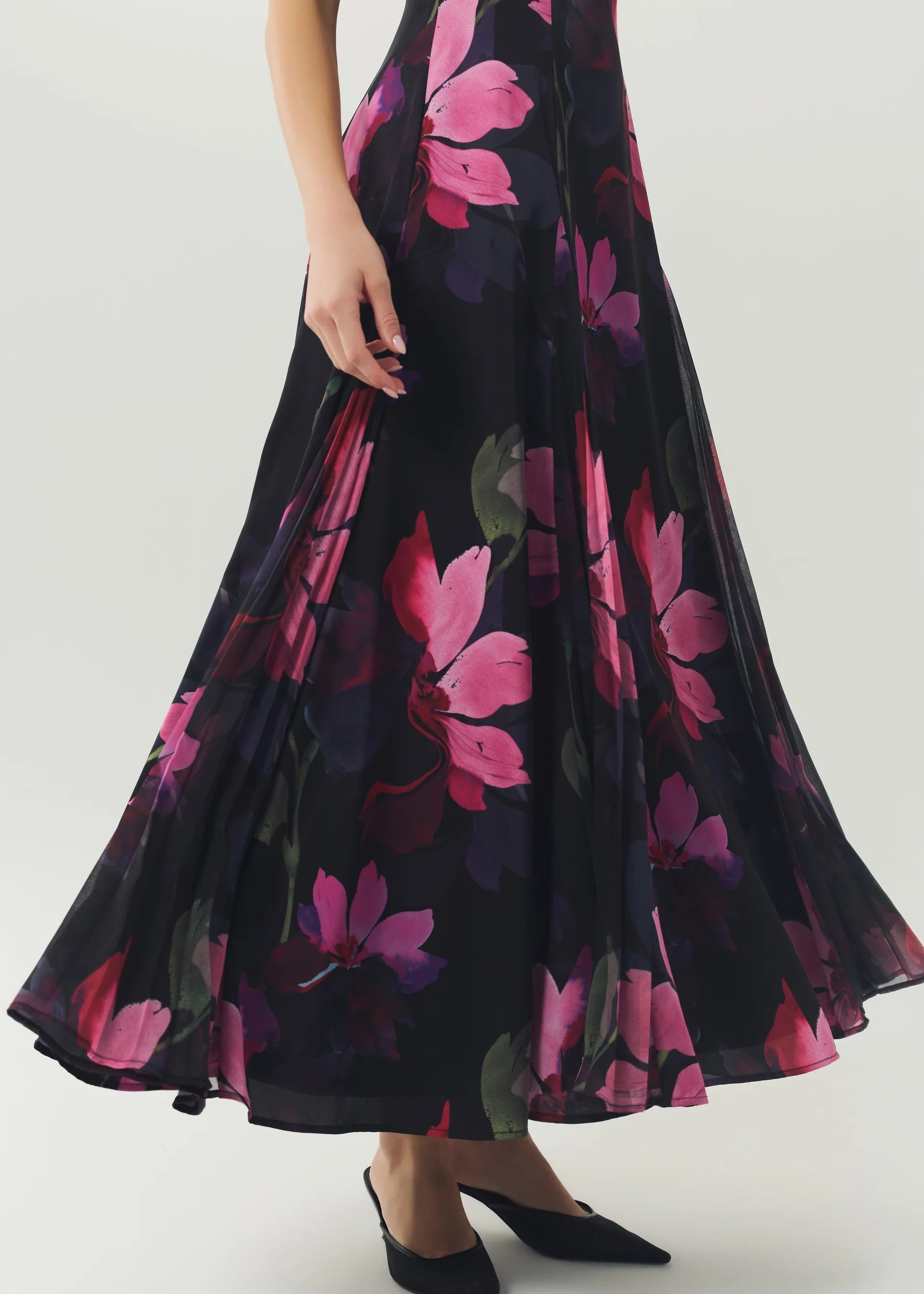 Woman wearing a black floral dress with pink flowers on a white background