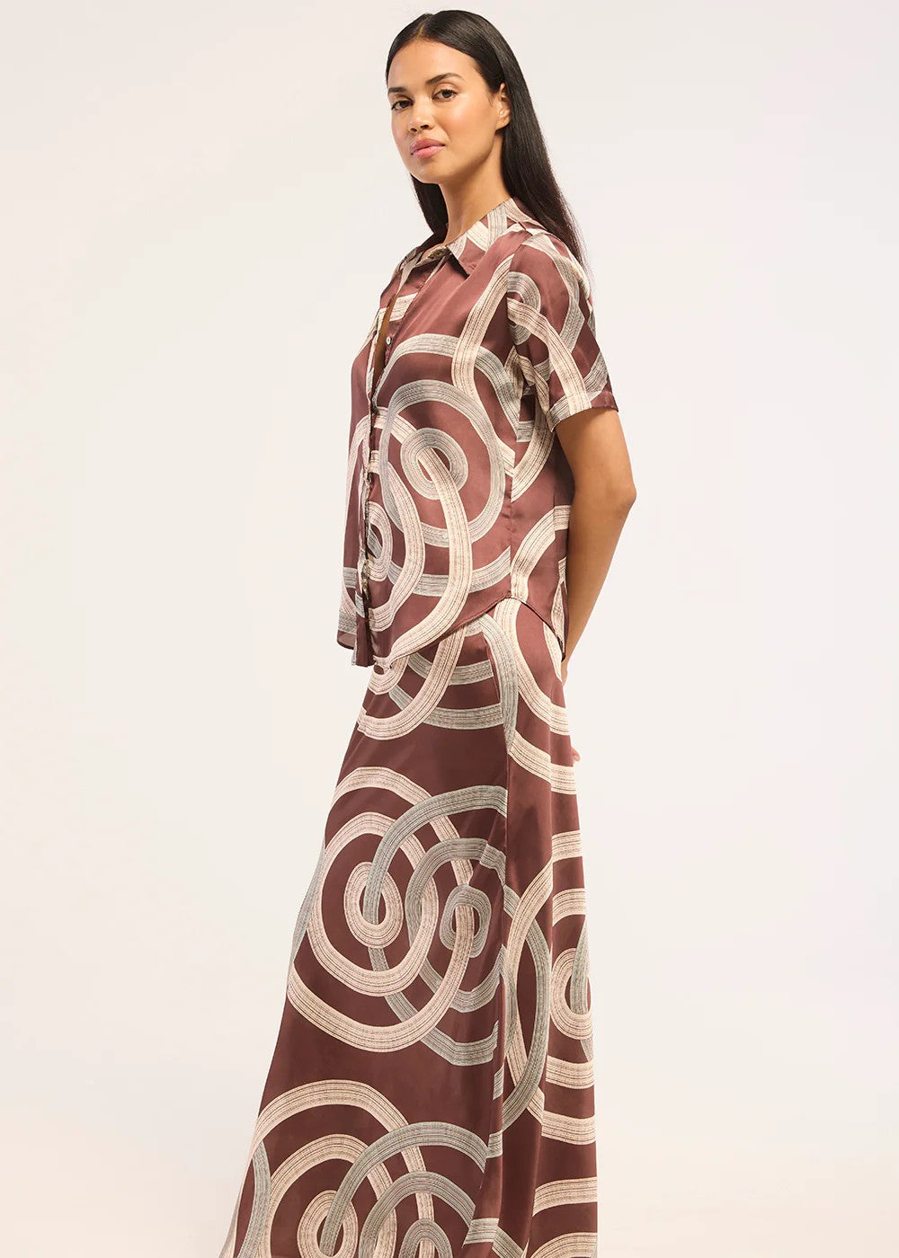 Woman wearing a long, patterned dress with a plain background