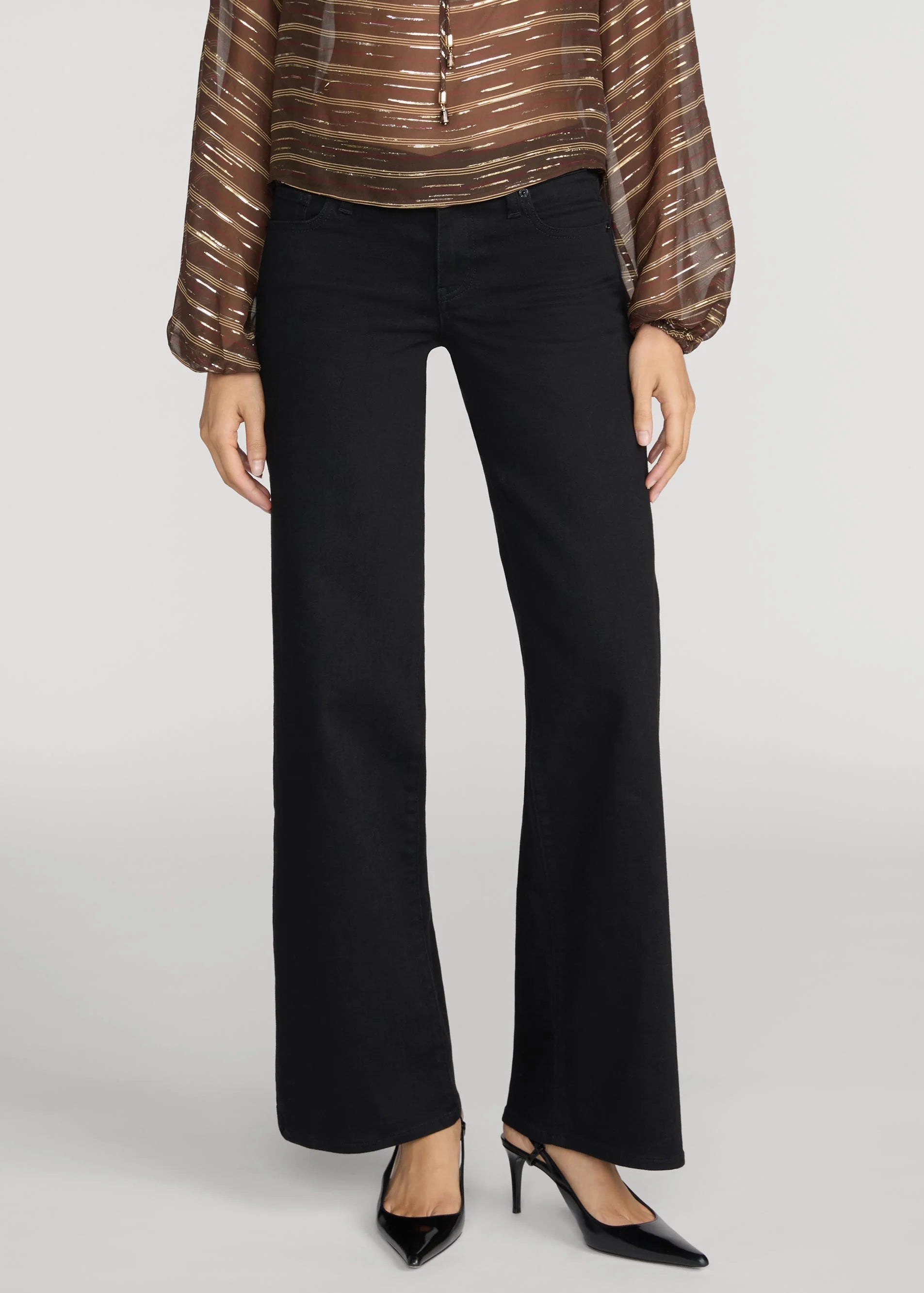 A model wearing black wide-leg flare pants, paired with a metallic bronze and brown striped blouse and black pointed-toe heels, against a light gray studio background.