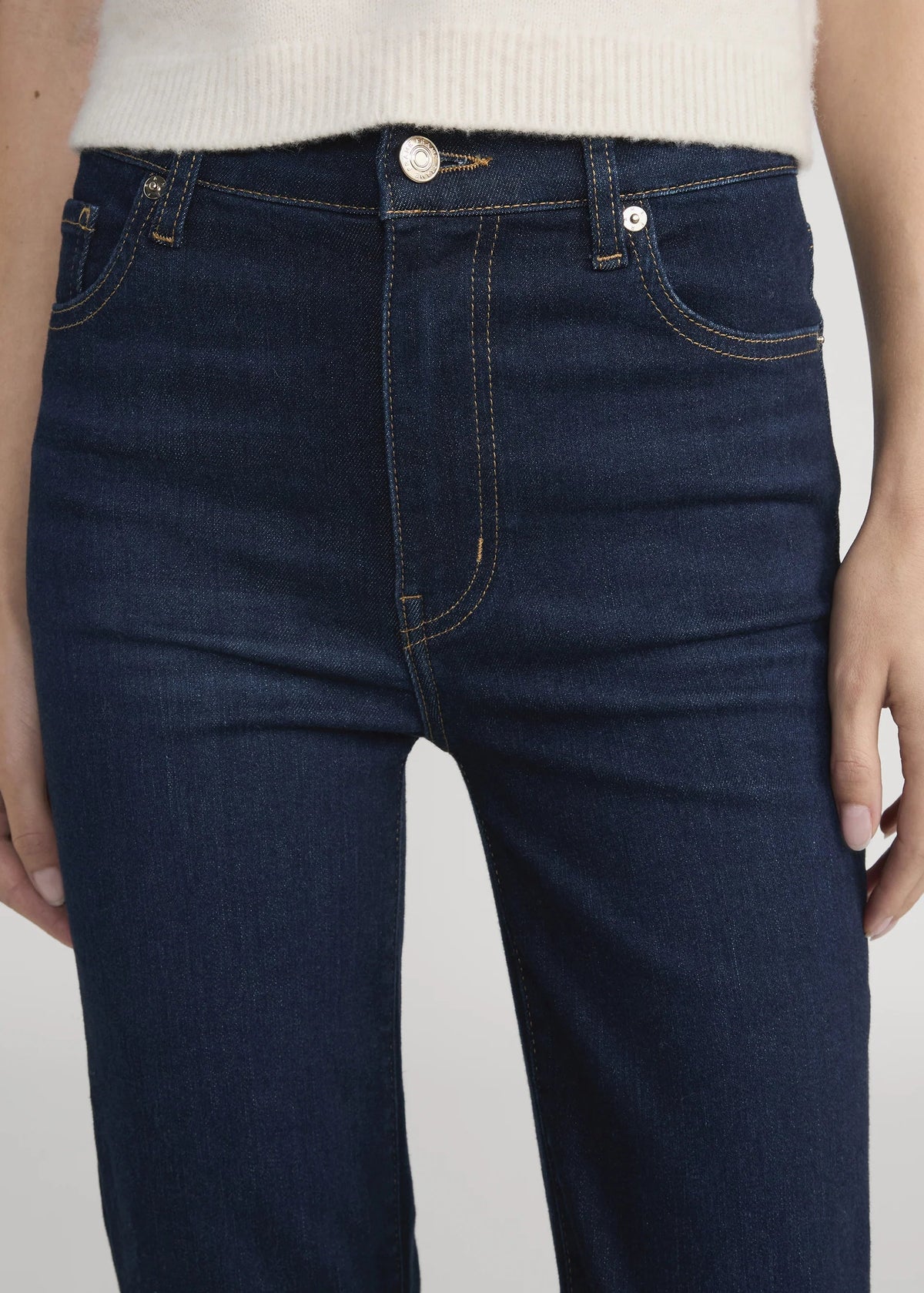 Dark blue jeans worn by a person on a plain background