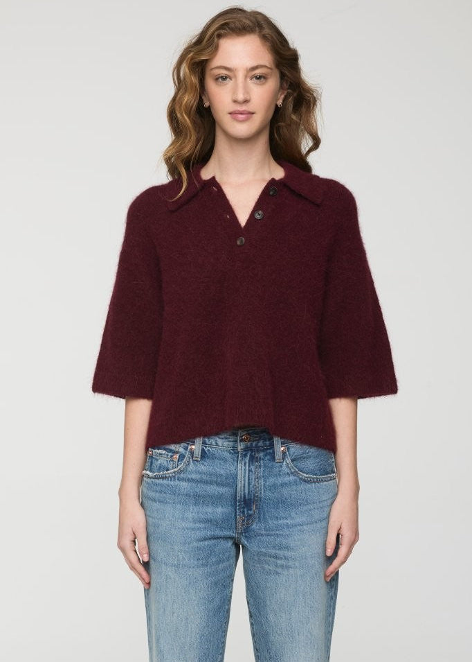 Woman wearing a burgundy short-sleeve shirt and blue jeans on a white background