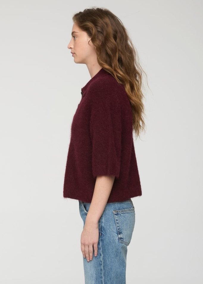 Woman wearing a burgundy sweater and blue jeans on a white background