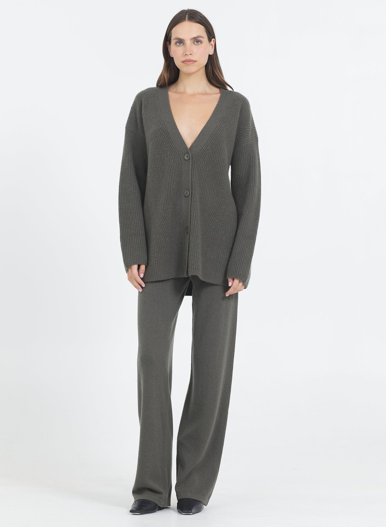 Woman wearing the One Grey Day Pacific cashmere cardigan in Fir green and pants on a white background