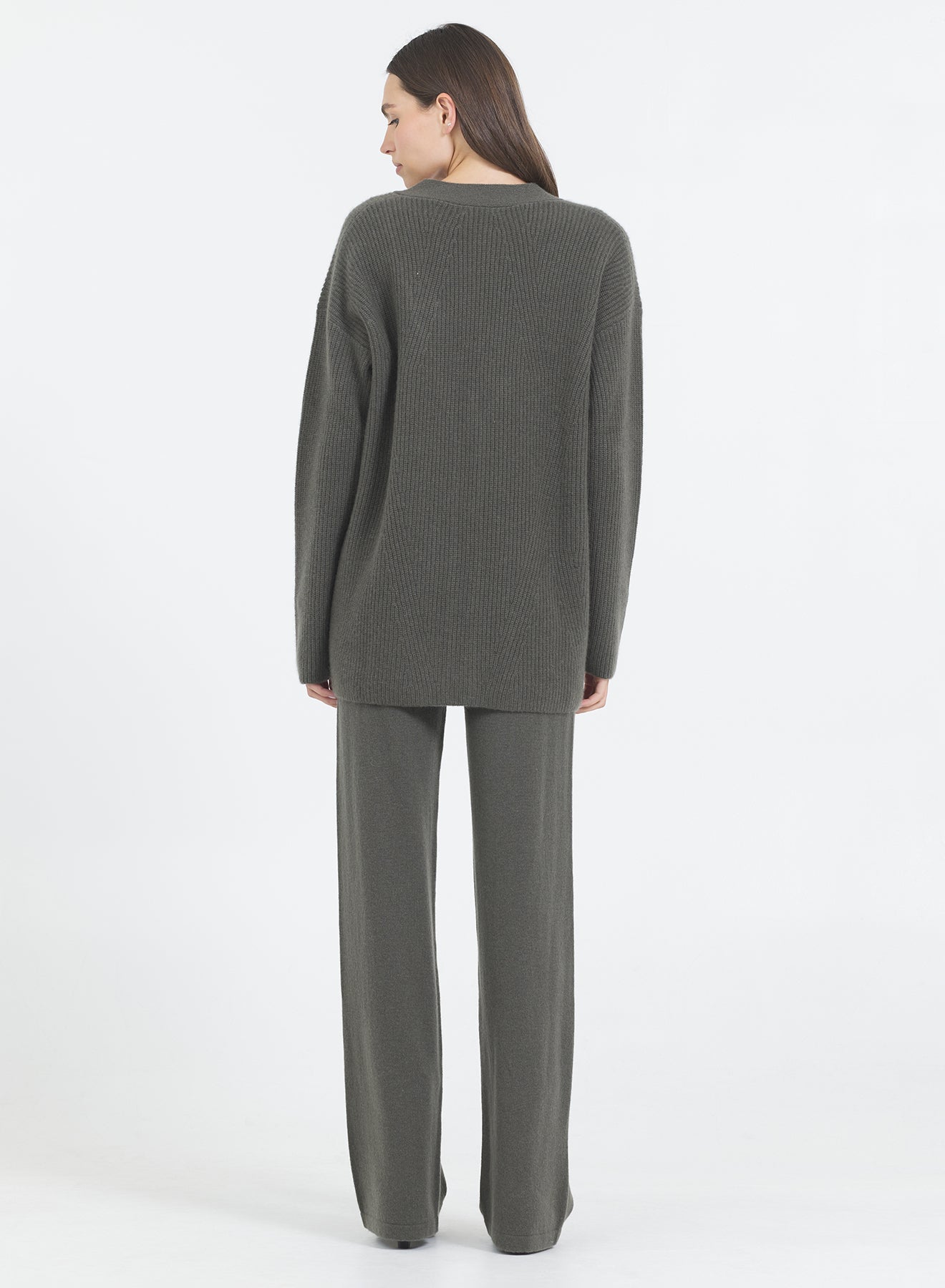 Woman wearing the Pacific One Grey Day fir green cashmere cardigan and pants on a white background