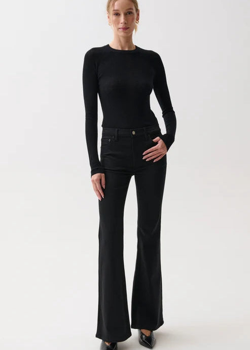 A woman modeling a black long-sleeve crewneck top and black flared pants against a plain light gray studio background.