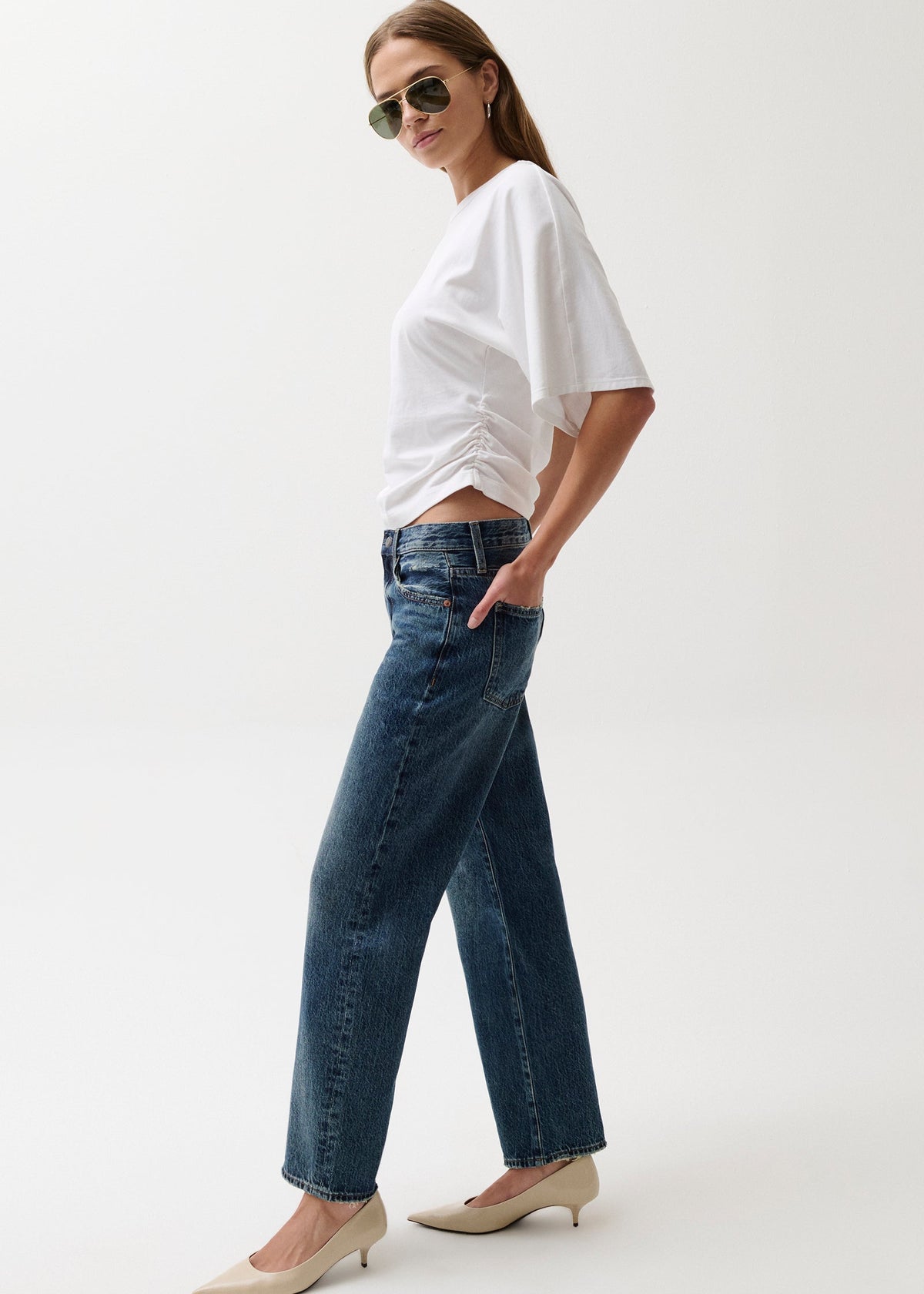 Woman wearing a white top and blue jeans on a white background