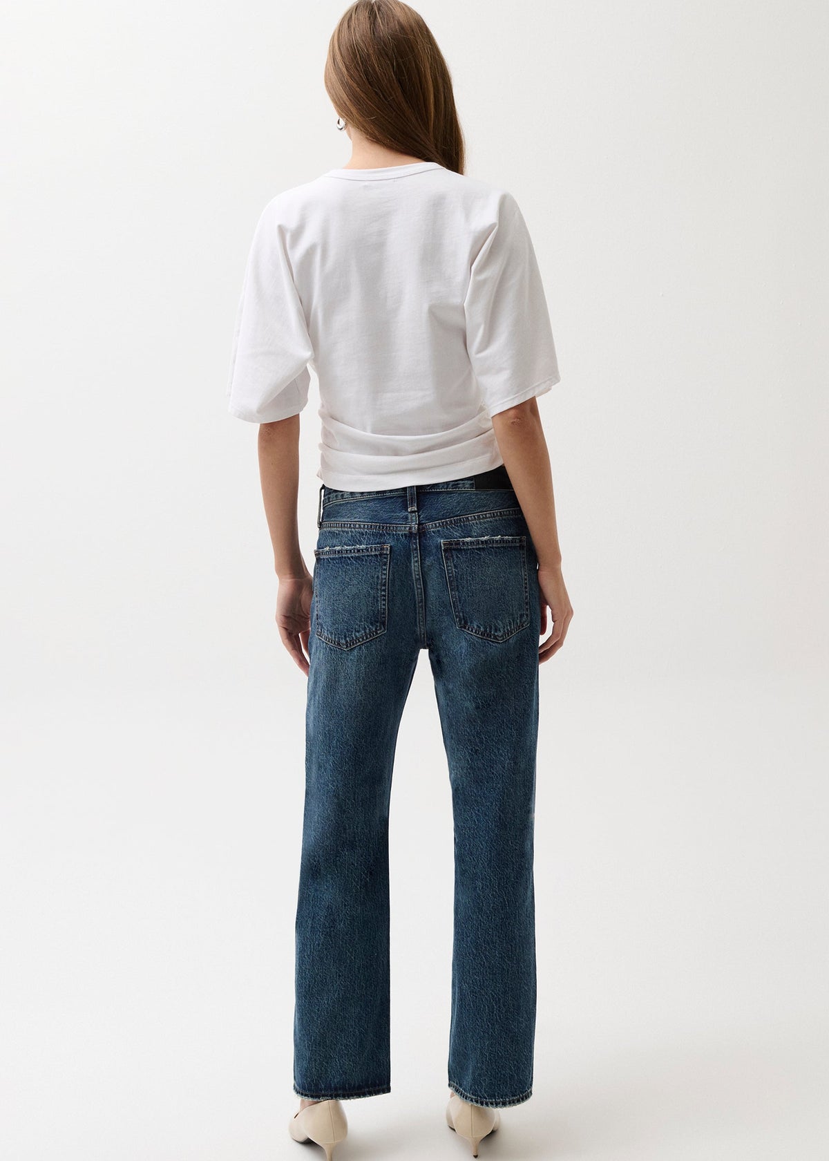 Person wearing a white shirt and blue jeans on a white background