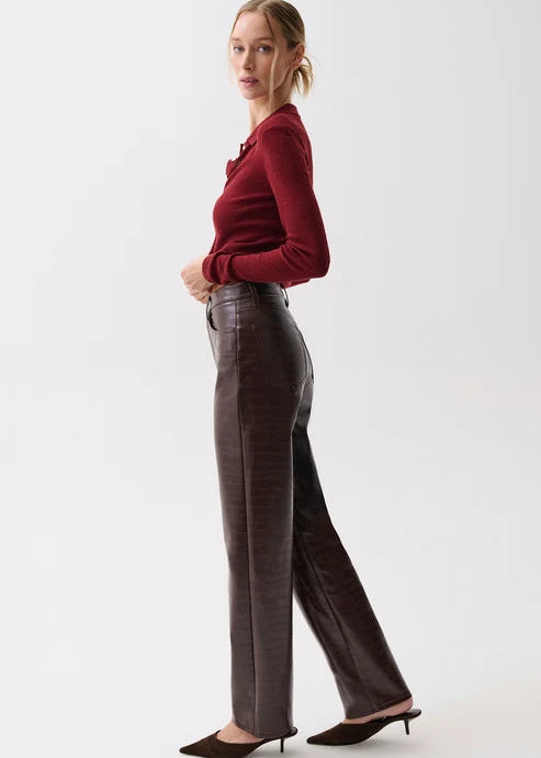 A woman modeling a pair of dark brown wide-leg trousers with a subtle textured pattern, paired with a burgundy long-sleeve top and dark brown pointed-toe mule heels, against a plain white studio background.