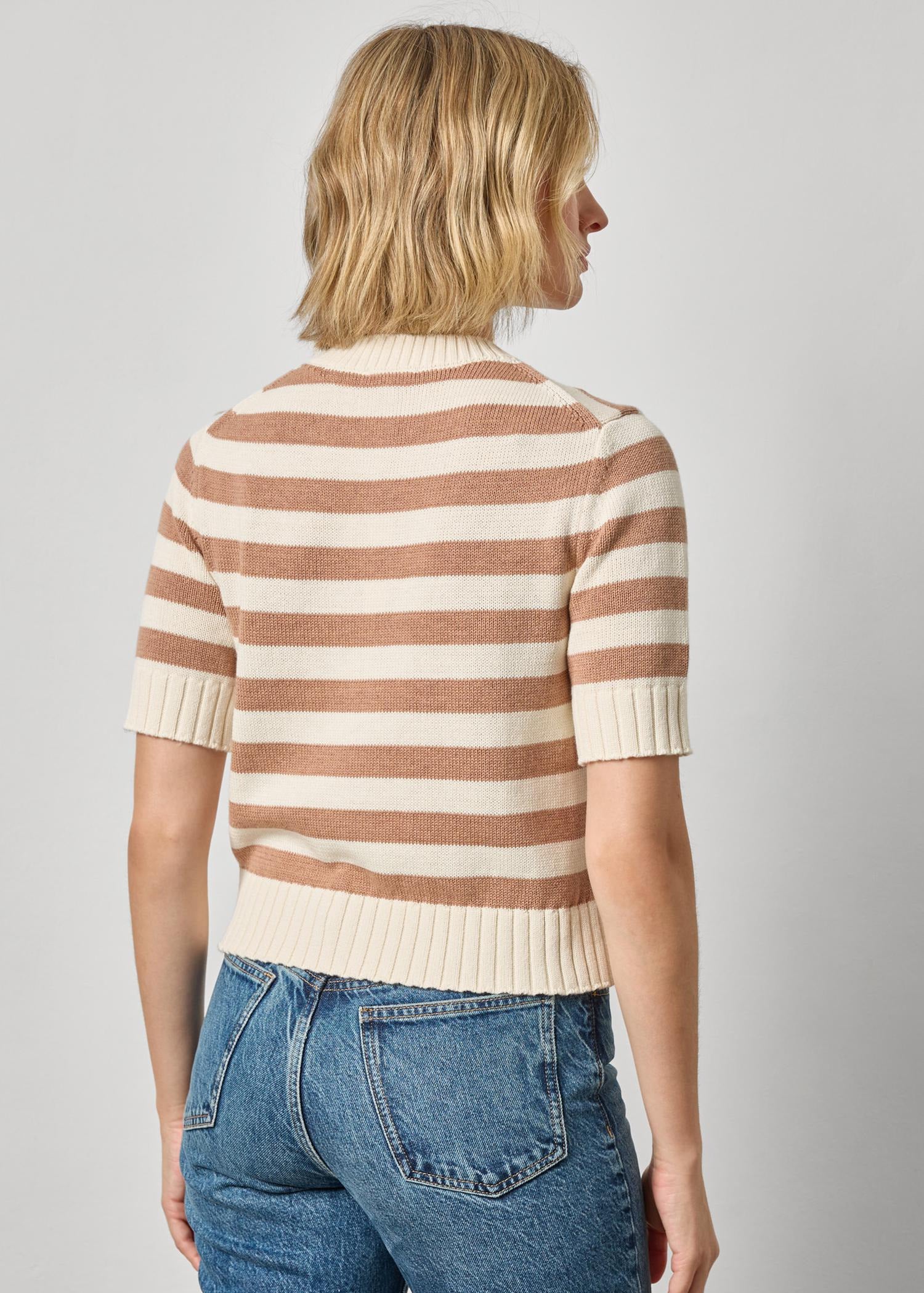 Woman wearing a striped sweater and jeans against a plain background