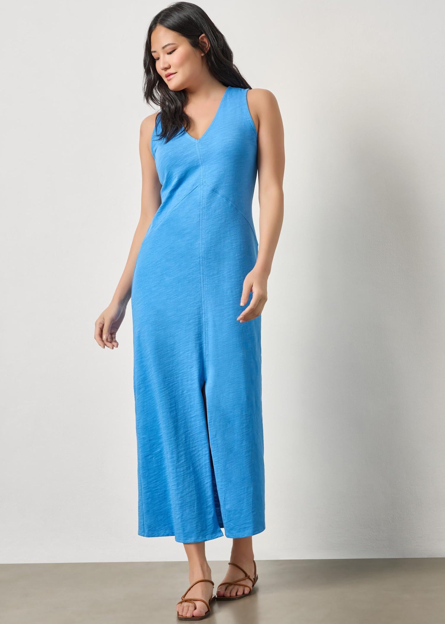 Woman wearing a blue sleeveless dress against a plain background