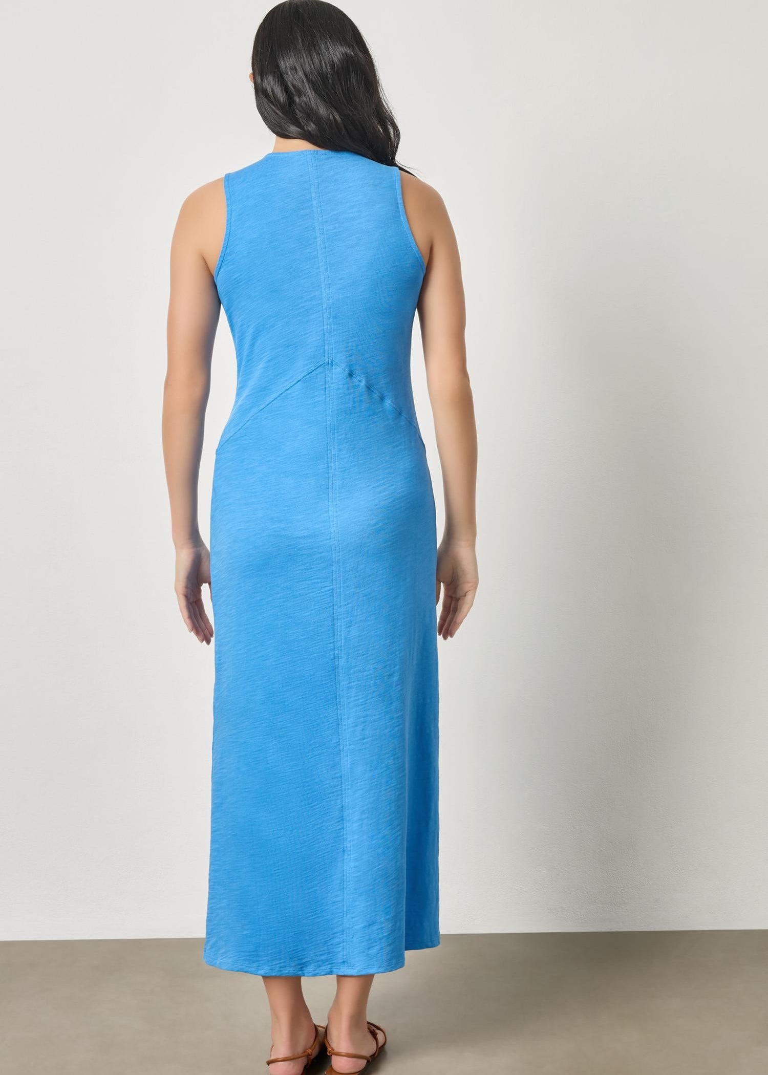Woman wearing a blue sleeveless dress against a plain background