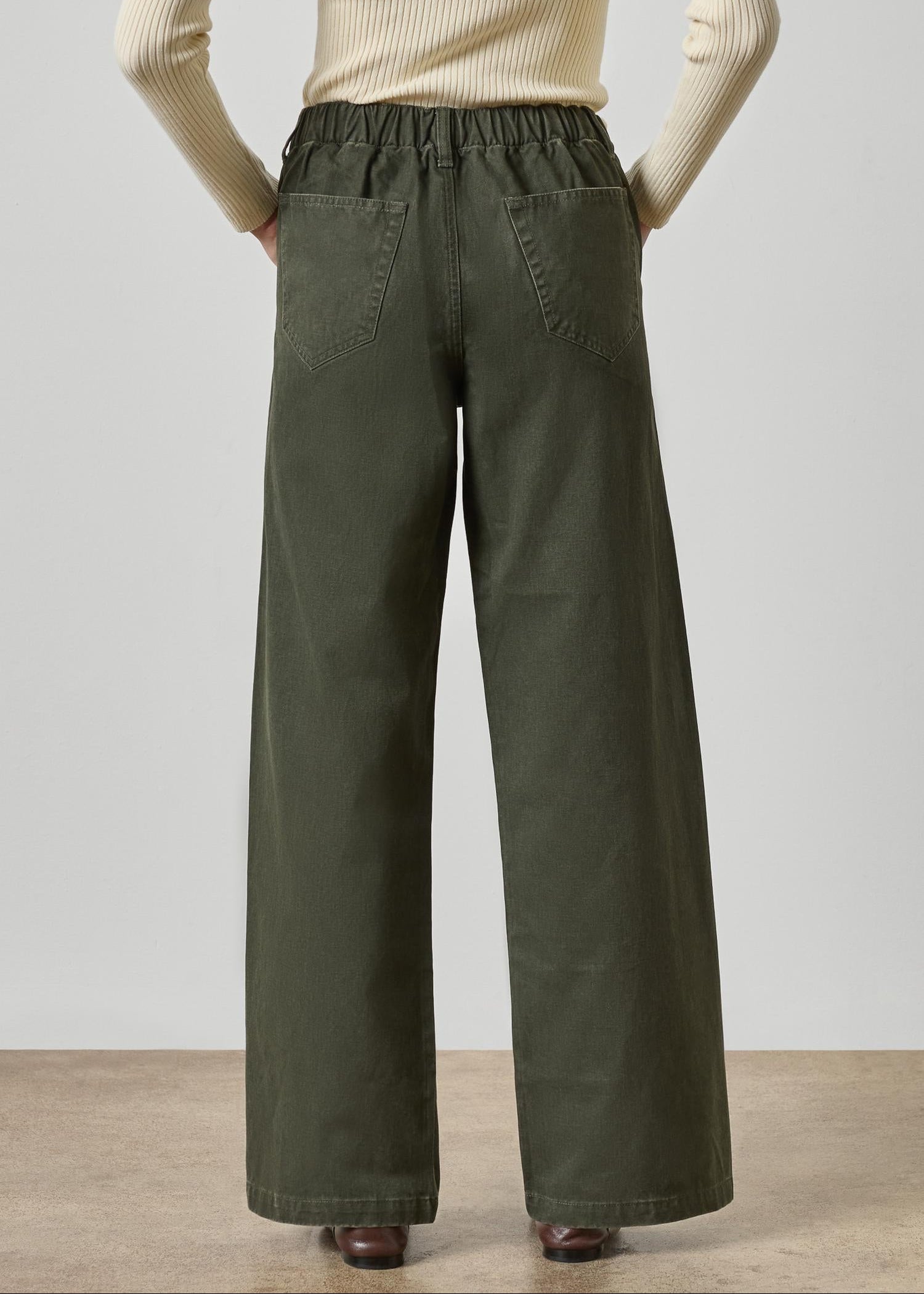 Person wearing olive green wide-leg pants with a plain background