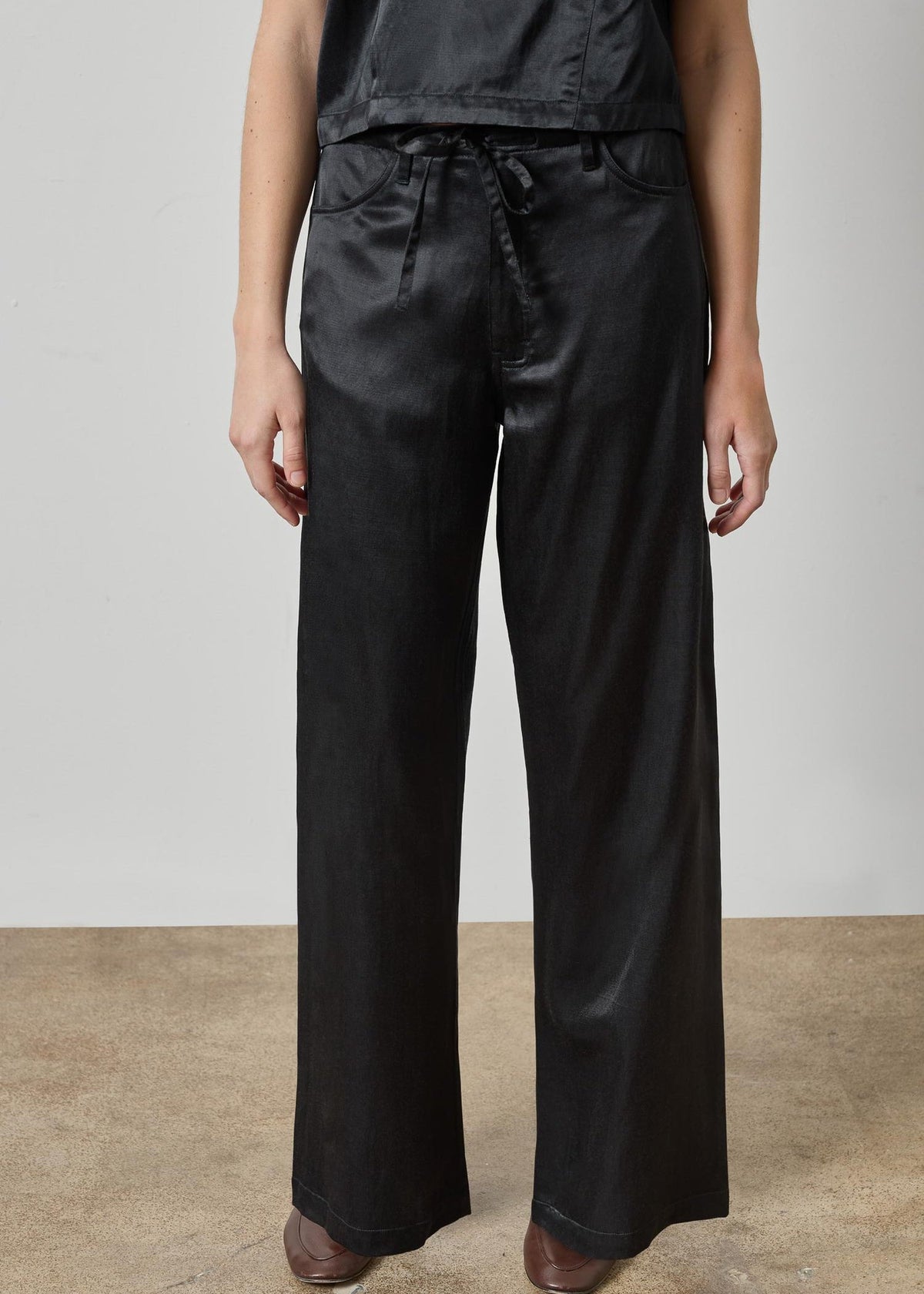 Person wearing black wide-leg pants on a plain background