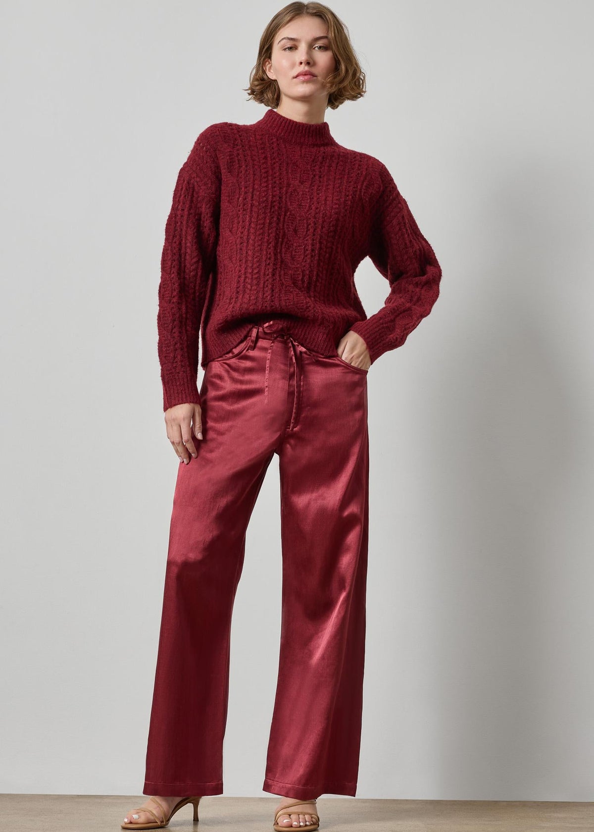Woman wearing a red sweater and pants against a plain background