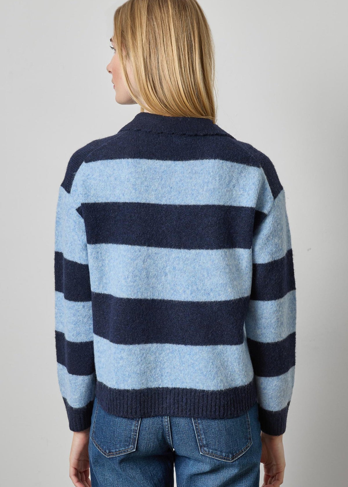 Person wearing a blue and navy striped sweater on a plain background