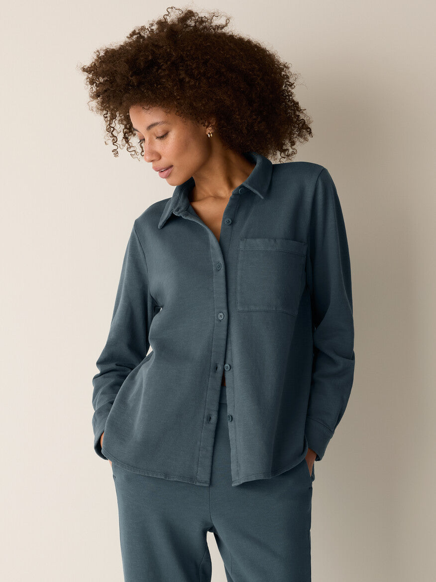 Woman wearing a teal shirt and pants against a beige background