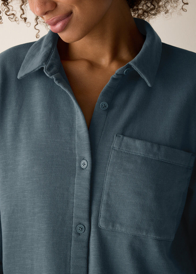 Close-up of a person wearing a dark blue button-up shirt with a pocket.