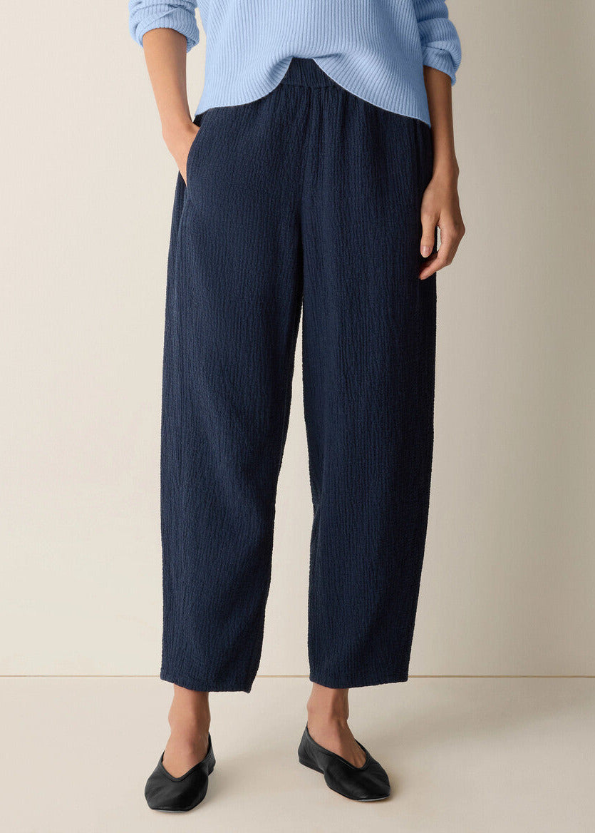 Person wearing navy wide-leg pants and a light blue top on a beige background