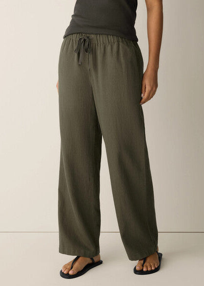 Person wearing olive green wide-leg pants on a plain background