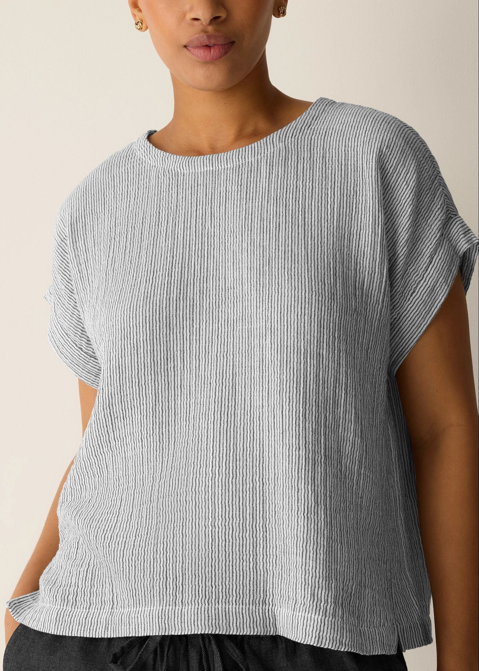 Woman wearing a gray and white striped shirt against a beige background