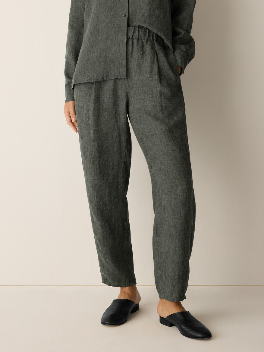 Person wearing a gray outfit with pants and a shirt on a beige background