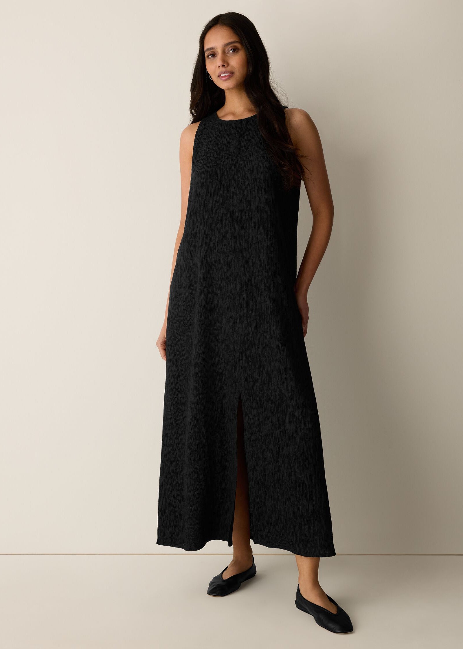 Woman wearing a black sleeveless dress against a plain background