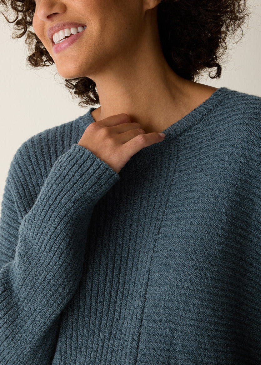 Person wearing a blue sweater with a neutral background