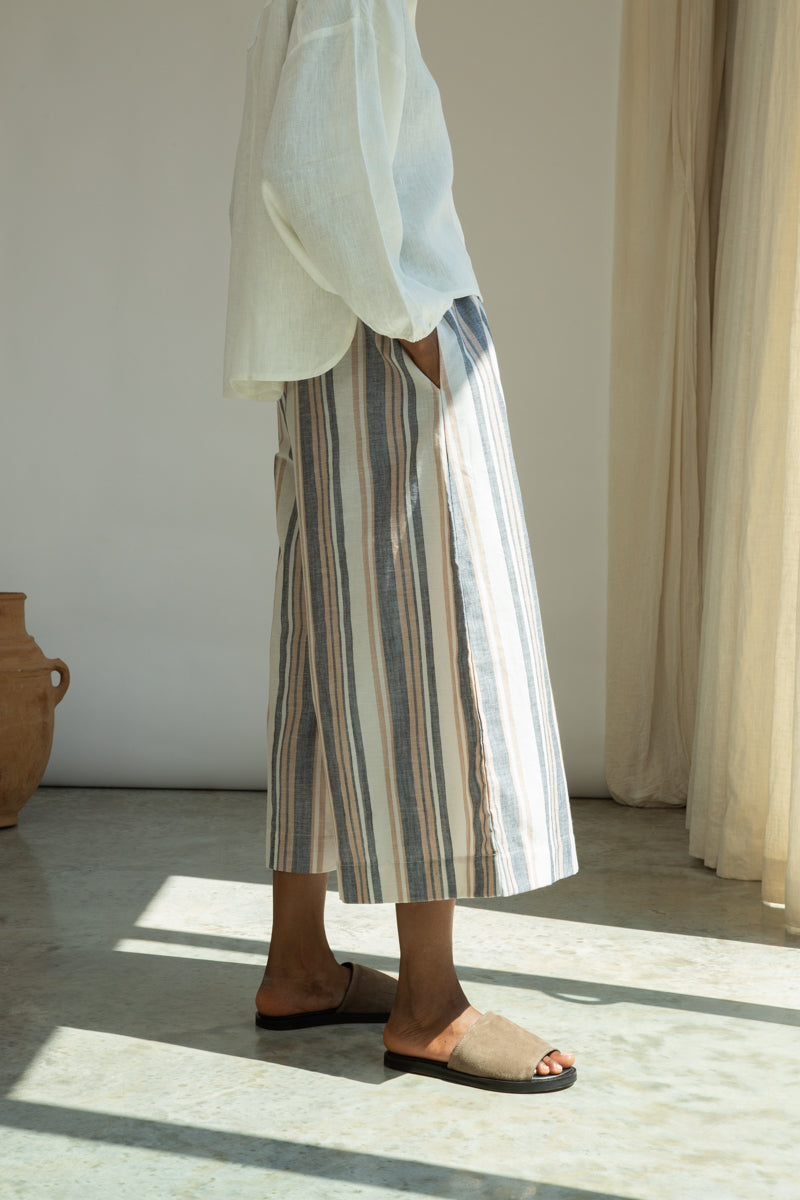 Person wearing striped pants and sandals in a room with a neutral color palette