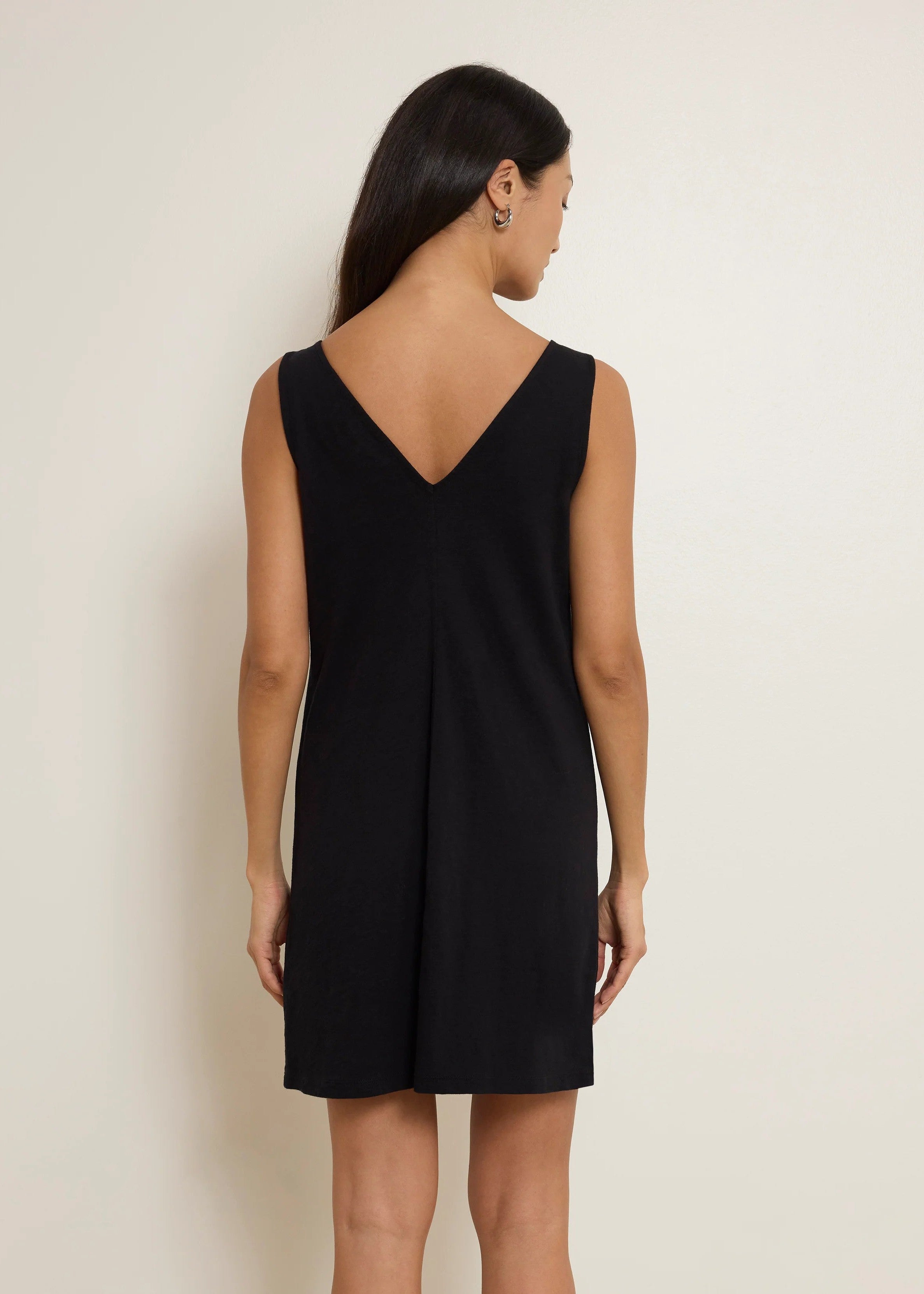 Woman wearing a black sleeveless dress against a plain background