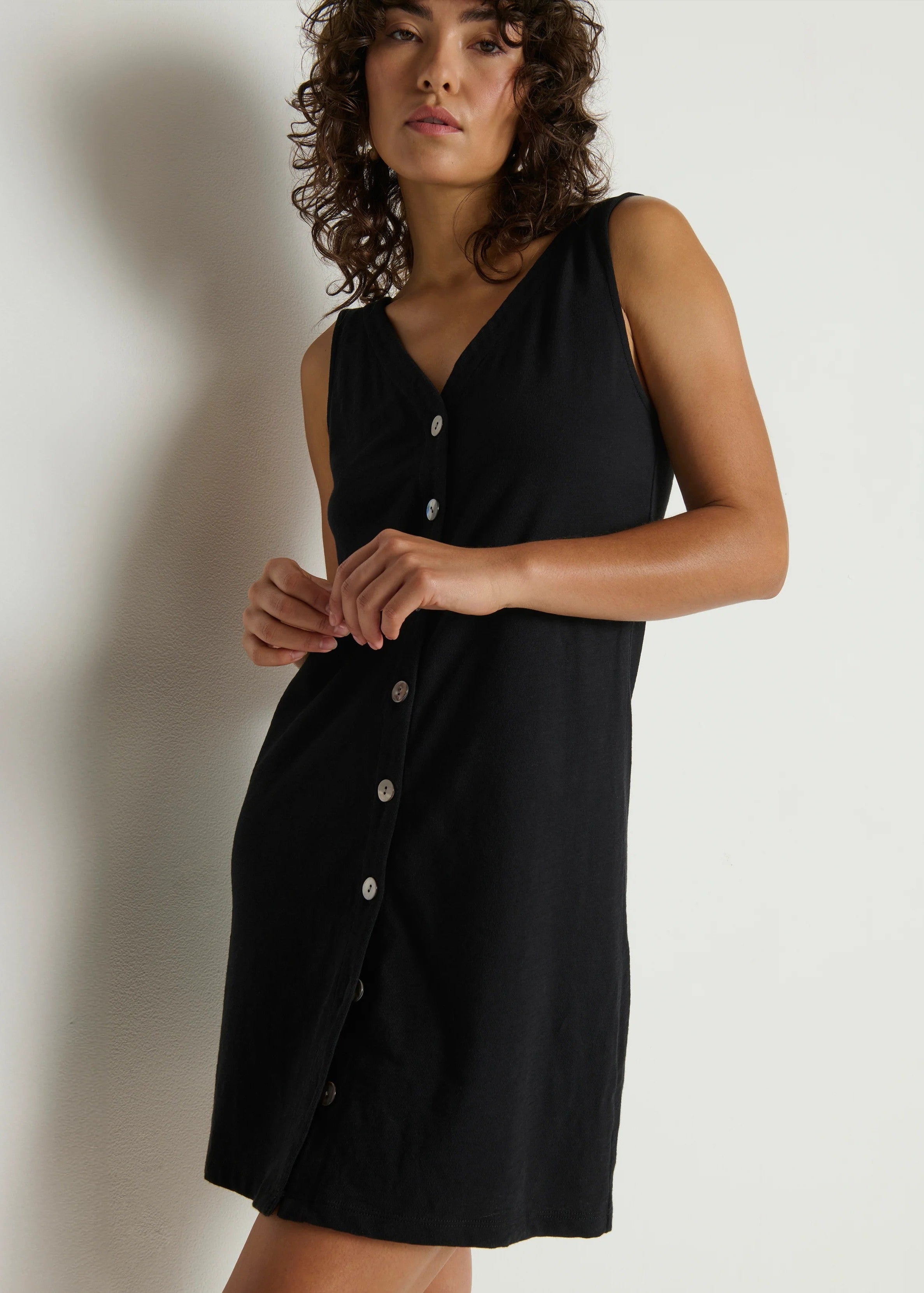 Woman wearing a black sleeveless dress against a plain background